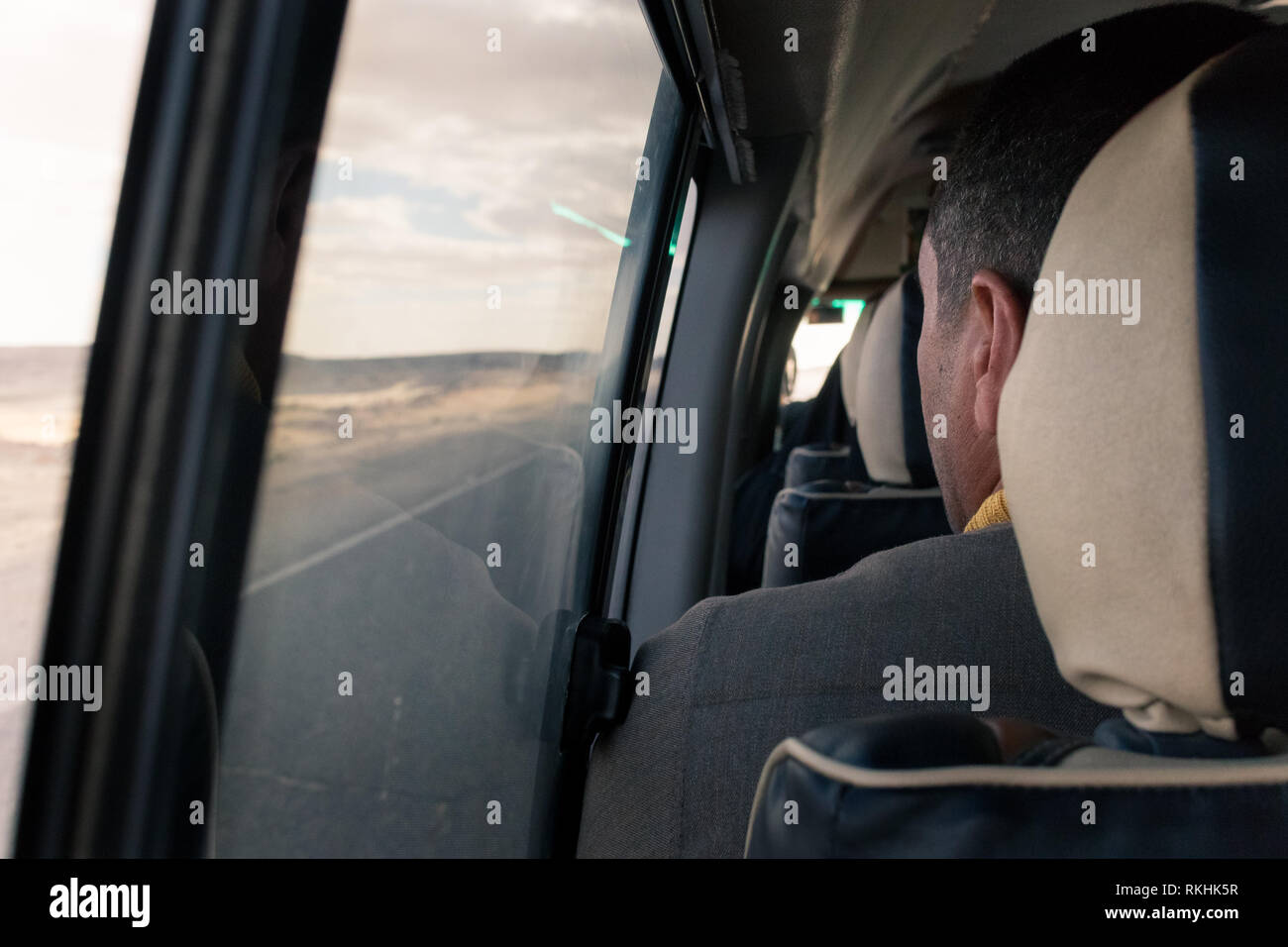 Un homme regarde au-dessus de la fenêtre dans un minibus (minibus) à voyager à travers le désert de l'Ouest en Egypte Banque D'Images