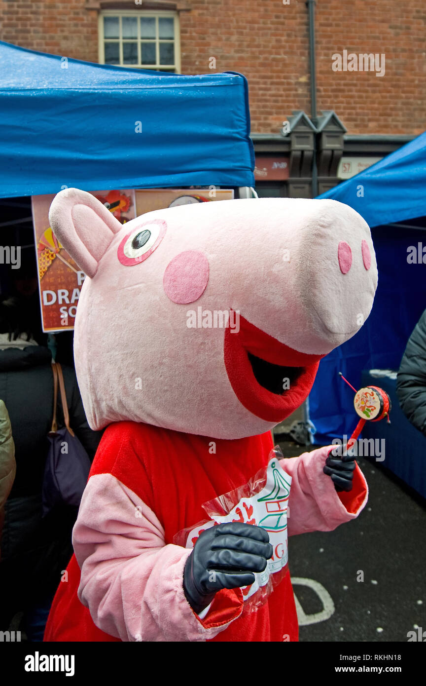 Une personne vêtue de Peppa Pig tenant un tambour chinois pendant les célébrations du nouvel an 2019 chinois pour célébrer l'année du Pig. Banque D'Images