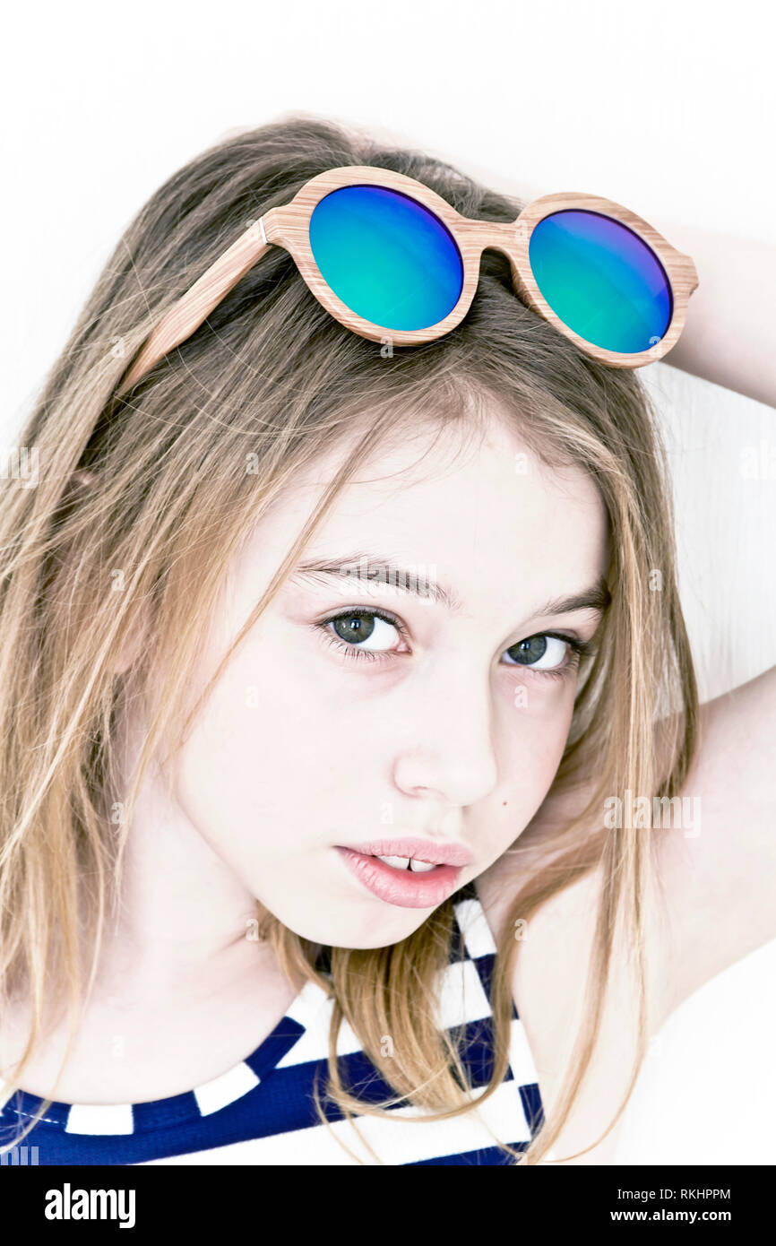 Fille blonde 11 ans, debout près de mur blanc avec des lunettes de soleil  vert Photo Stock - Alamy