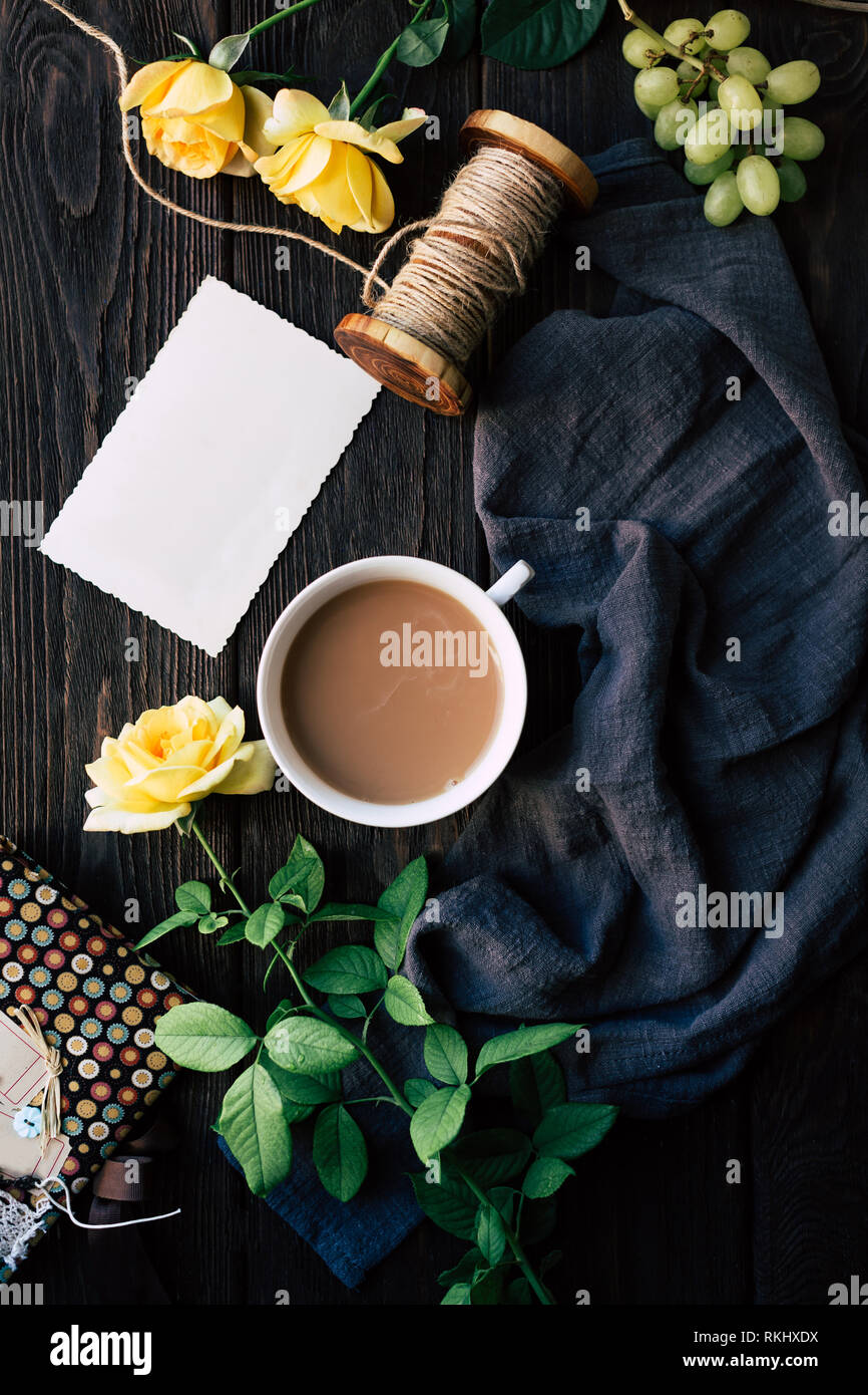 Au-dessus de belles roses jaunes et blancs remarque situées près de tasse de café sur la table de bois au milieu de morceau de tissu bleu avec fil de lin et de ri Banque D'Images