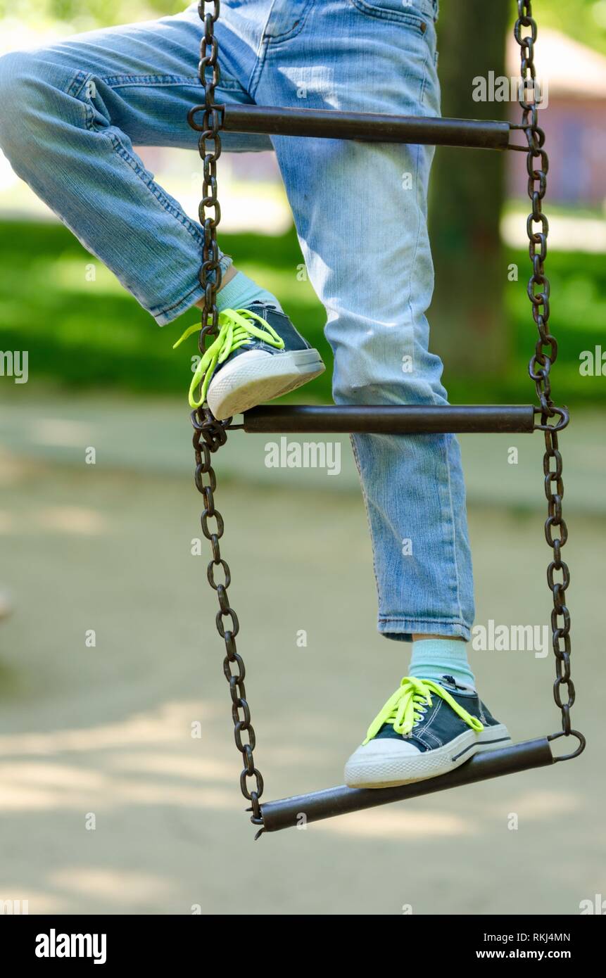 Les jambes d'un enfant dans des chaussures à lacets vert clair sur une  échelle en métal sur les chaînes Photo Stock - Alamy
