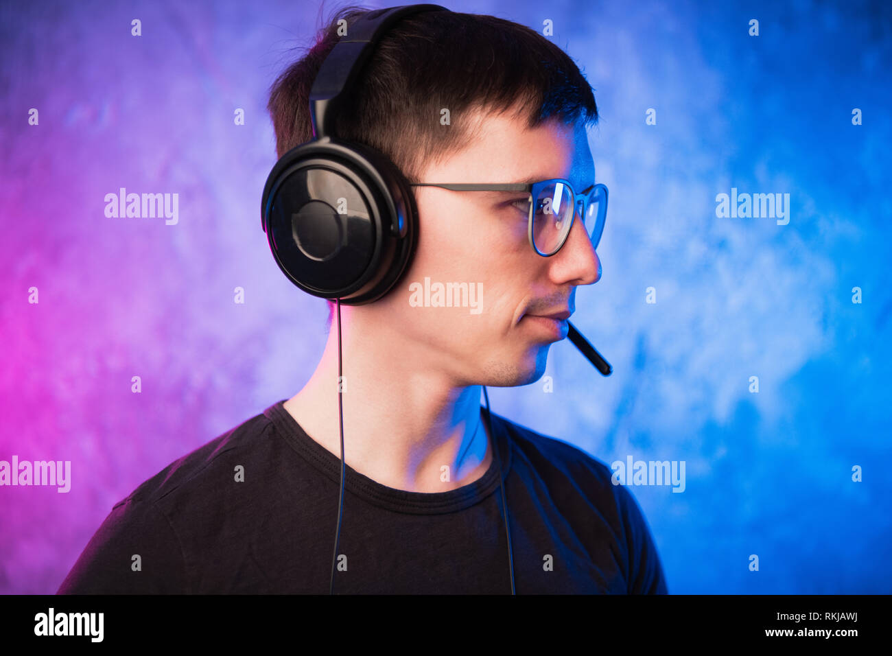 Gamer ou streamer des écouteurs avec microphone sur rose et bleu coloré éclairé au néon wall Banque D'Images