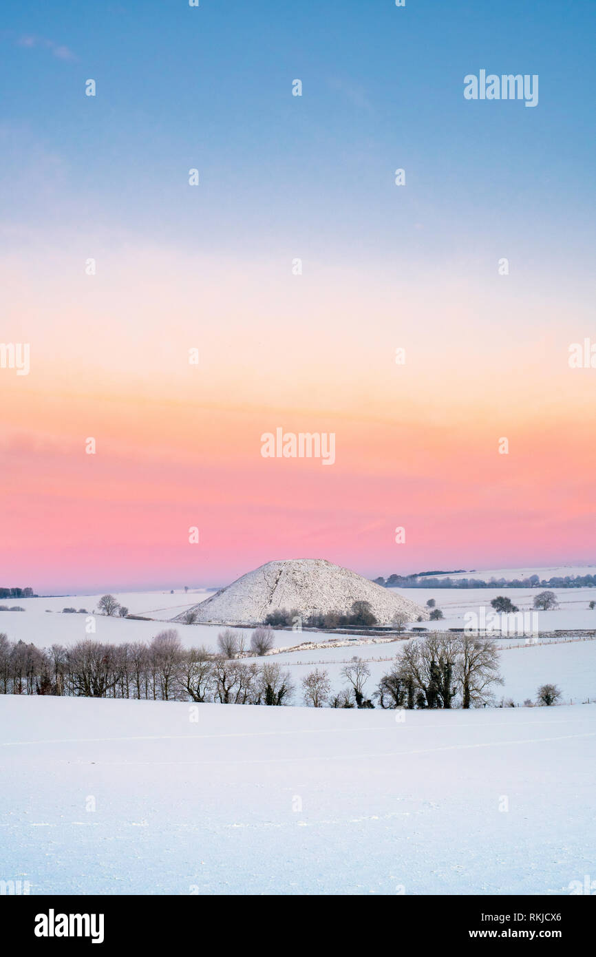 Silbury Hill dans la neige de l'hiver au crépuscule avant le lever du soleil. Avebury, dans le Wiltshire, Angleterre Banque D'Images