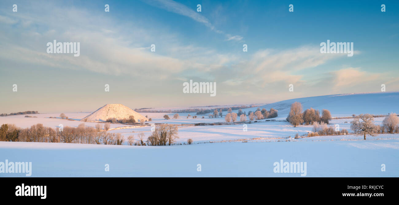 Silbury Hill dans la neige de l'hiver au lever du soleil. Avebury, Wiltshire, Angleterre. Vue panoramique Banque D'Images