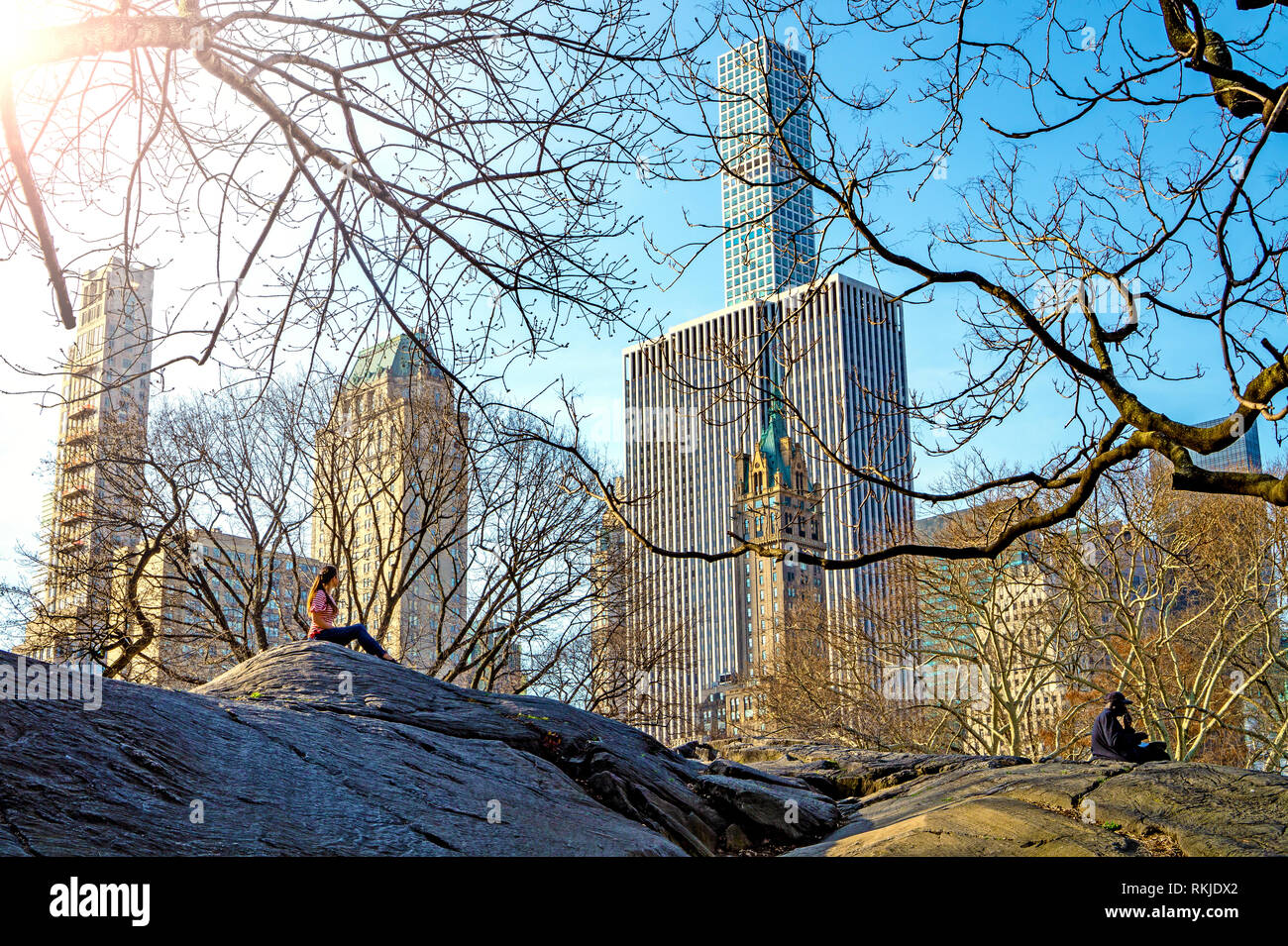 Les gens de traîner dans le beau temps sur un gros rocher dans Central Park New York avec des gratte-ciel en arrière-plan Banque D'Images
