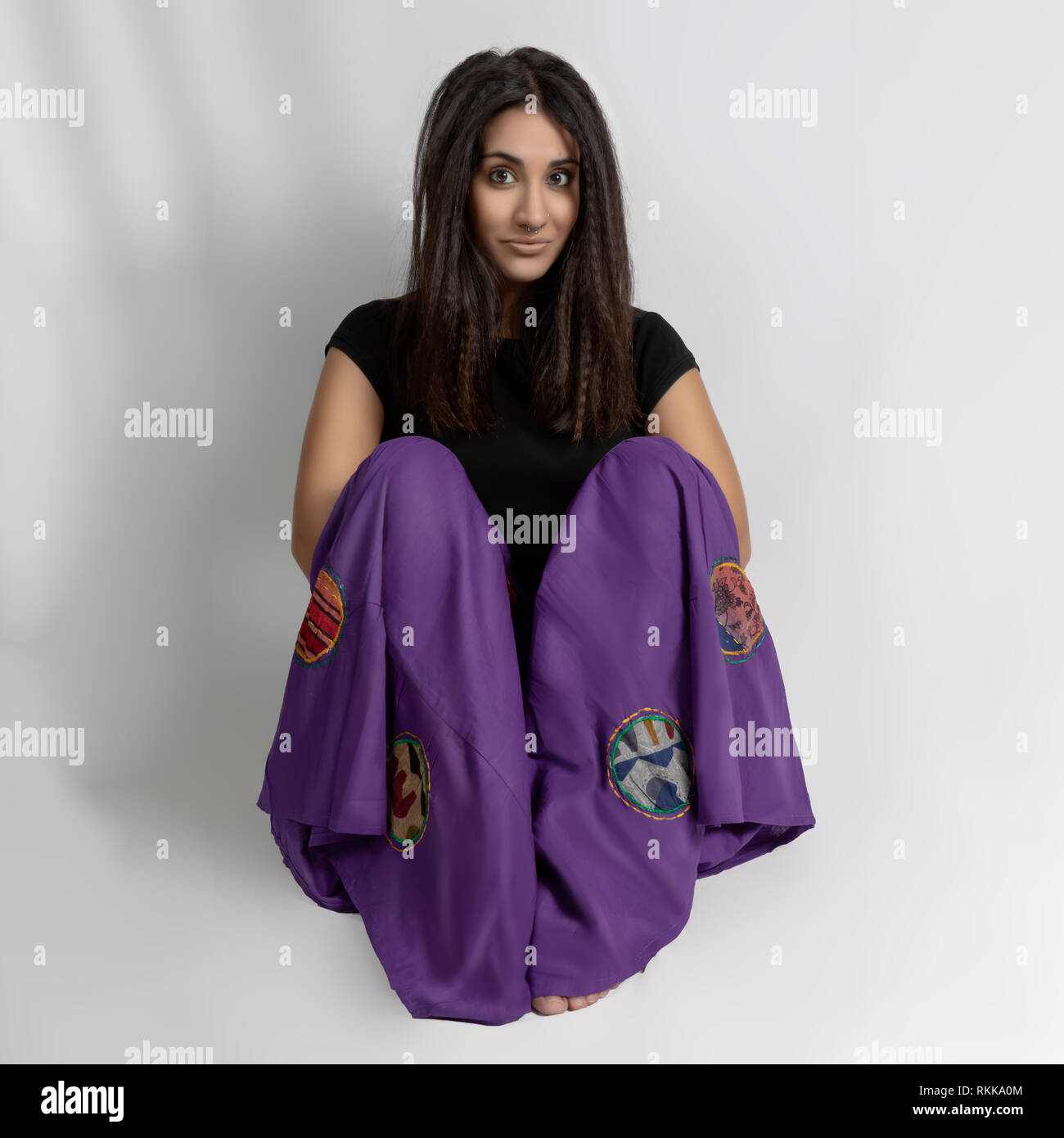 Pretty girl sitting on floor with purple pantalon oriental. Banque D'Images