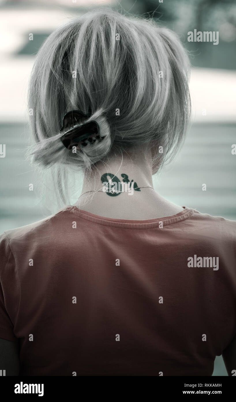 Femme aux cheveux couleur de cendre et la nuque tatouée debout dans la rue. Banque D'Images