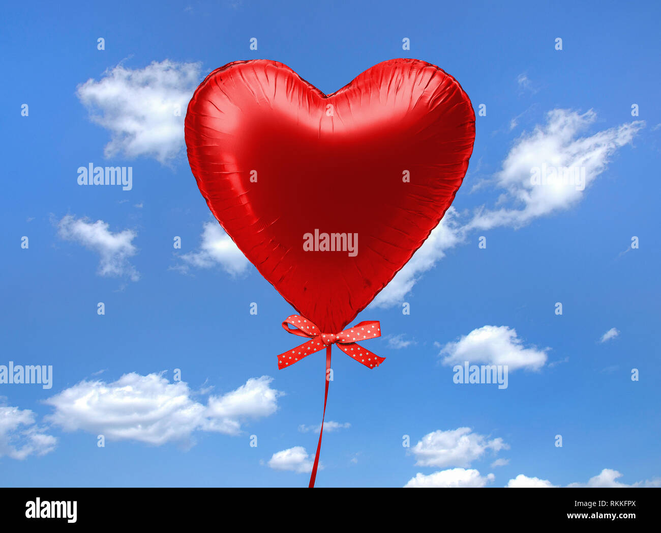 Coeur rouge hélium ballon flottant dans ciel avec polka dot bow Banque D'Images