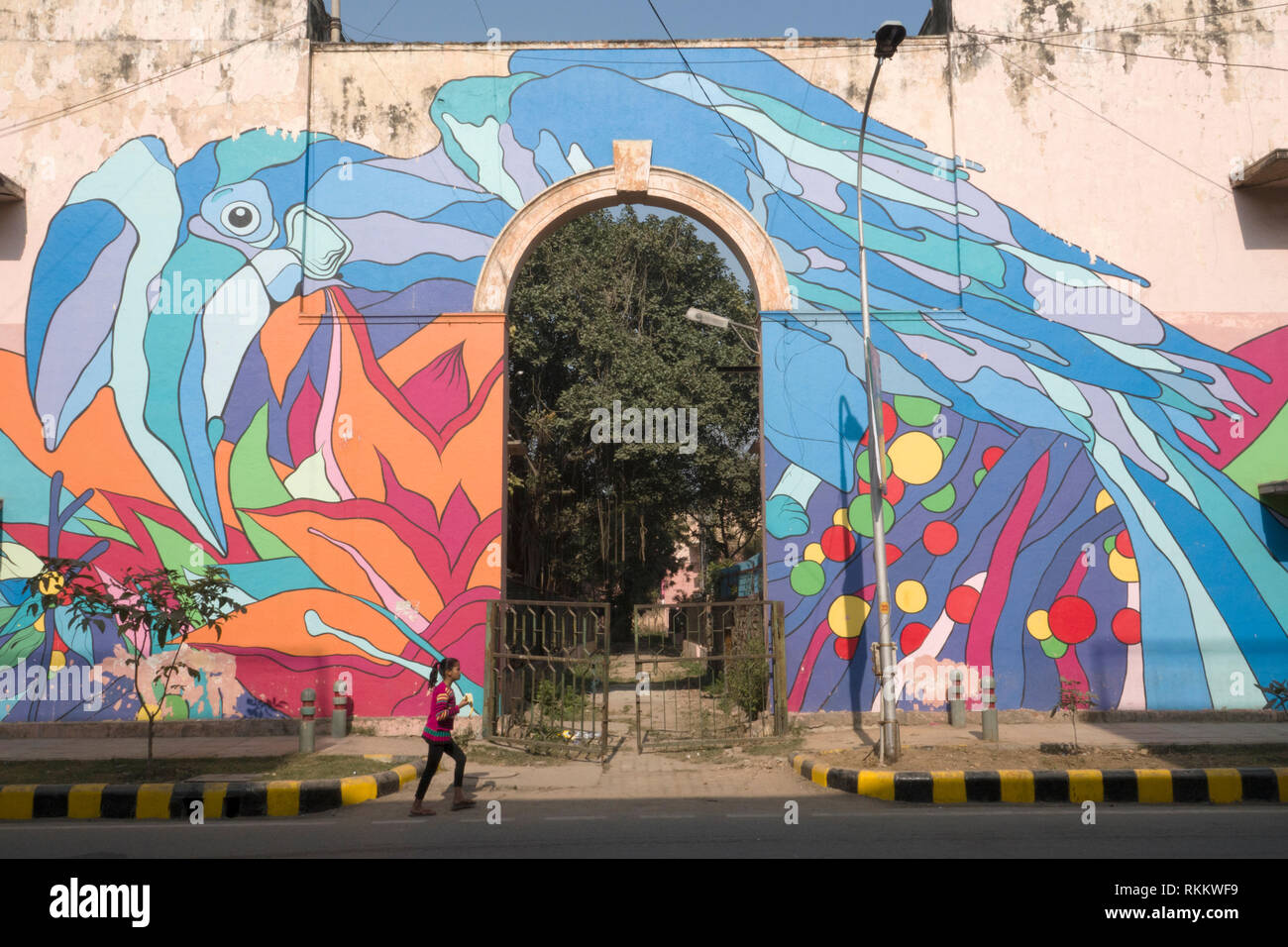 Une fille passe devant une peinture murale de la rue d'un Calao Pie Oriental par Renato Reno de Lodhi Colony, New Delhi, Inde Banque D'Images