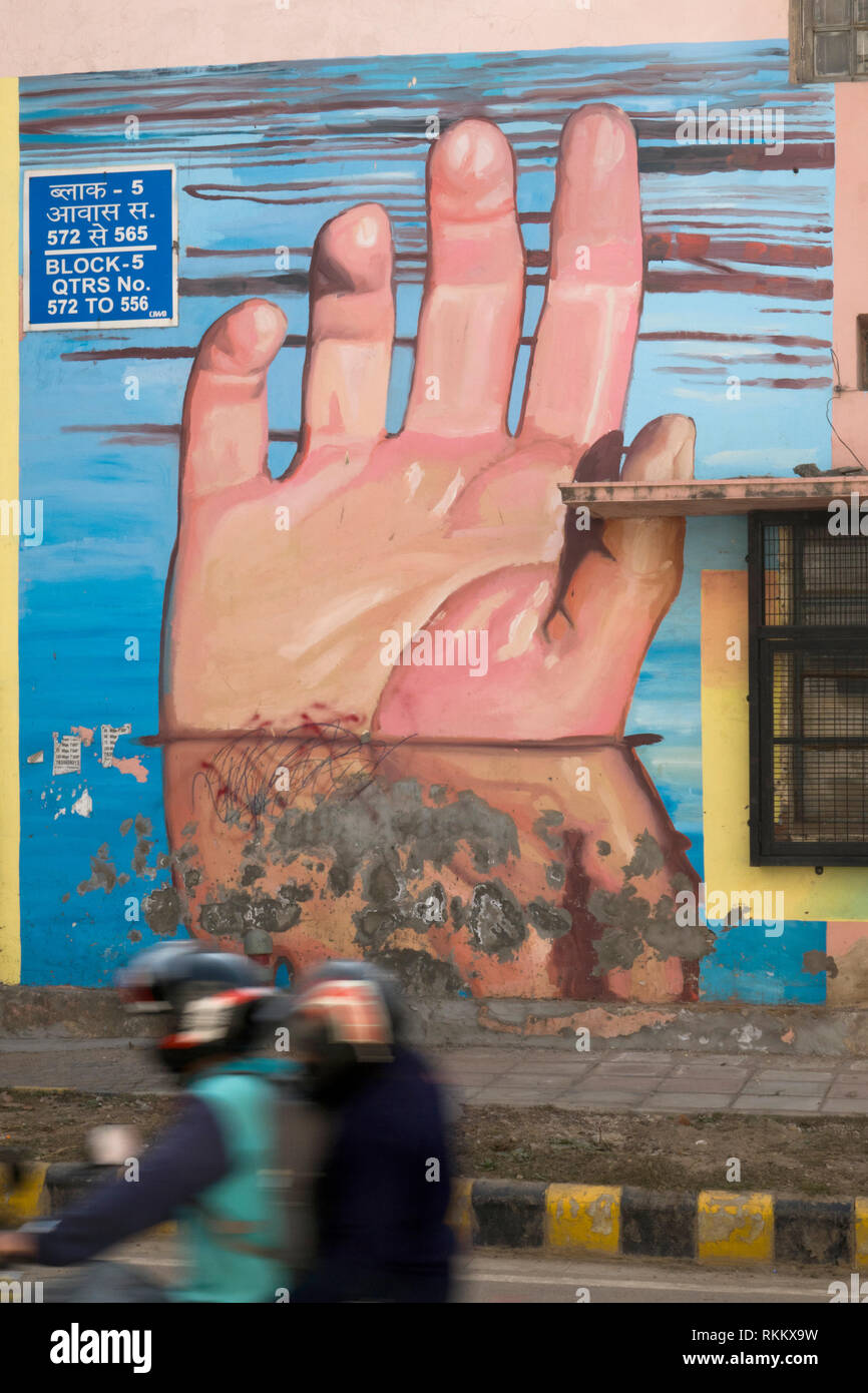 Un couple sur moto passer une murale intitulée mains sous l'eau par artiste Gaia, dans Lodhi Colony, New Delhi, Inde Banque D'Images