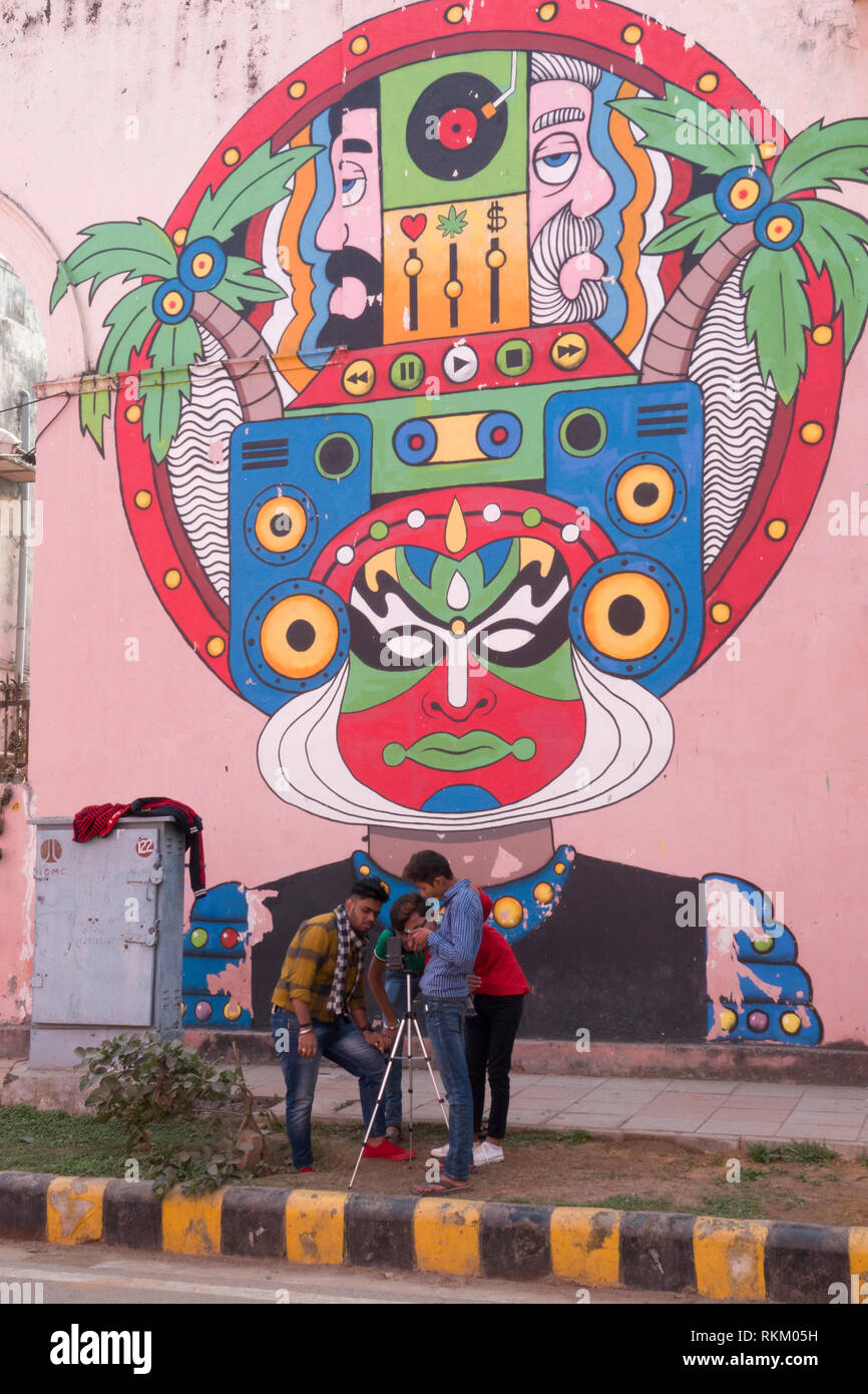Groupe de jeunes hommes de filmer en face de la rue grande murale de l'artiste indien Raman, dures dans Lodhi Colony, New Delhi, Inde Banque D'Images