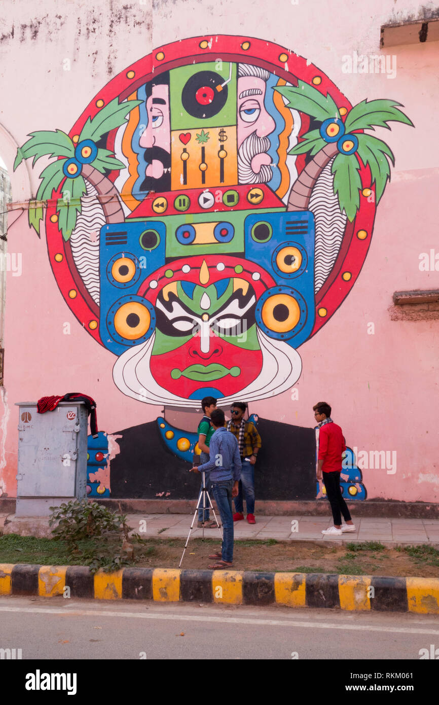 Groupe de jeunes hommes de filmer en face de la rue grande murale de l'artiste indien Raman, dures dans Lodhi Colony, New Delhi, Inde Banque D'Images
