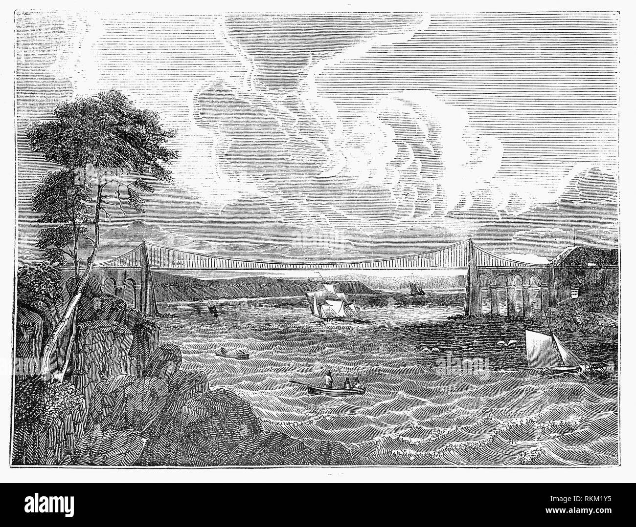 Le Pont Suspendu de Menai, transporte le trafic routier entre l'île d'Anglesey et de la partie continentale du pays de Galles. Avant que le principal moyen d'accès était en ferry à travers le courant rapide et les eaux dangereuses du détroit de Menai. Parce qu'Holyhead était l'un des principaux ports de ferries à destination de Dublin, l'ingénieur Thomas Telford a été engagé pour répondre à une enquête de la route de Londres à Holyhead. Parce que le pont doit être suffisamment élevé pour permettre le passage des grands voiliers, Telford a proposé qu'une suspension pont est construit ; sa recommandation a été acceptée et le pont est inauguré en 1826. Banque D'Images