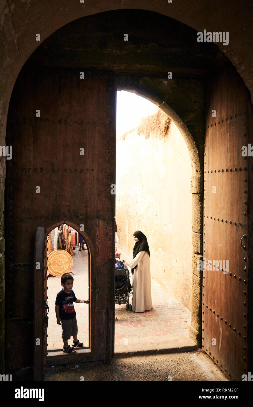 Une famille se dresse tout en pans de bois par une grande porte dans Essaouira. Banque D'Images