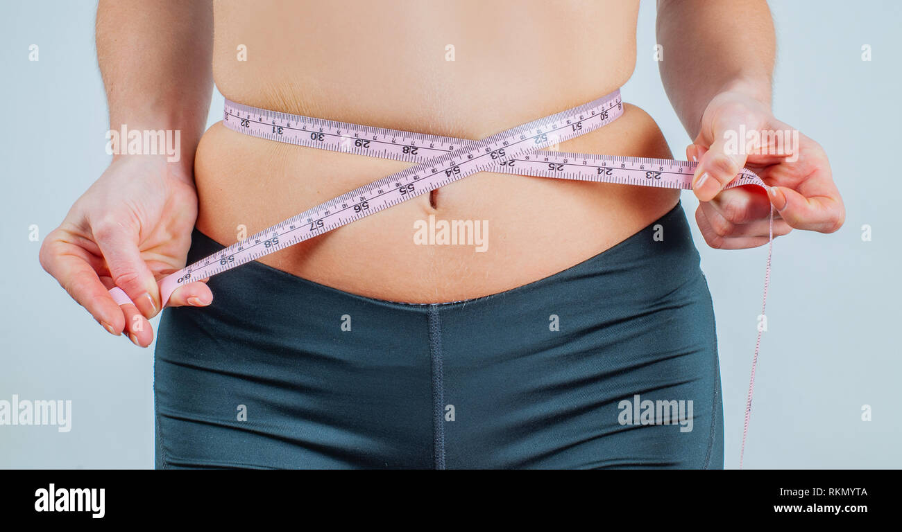 L'excès de femme avec ruban à mesurer autour de la taille. La mesure de sa  taille femme ventre gras Photo Stock - Alamy