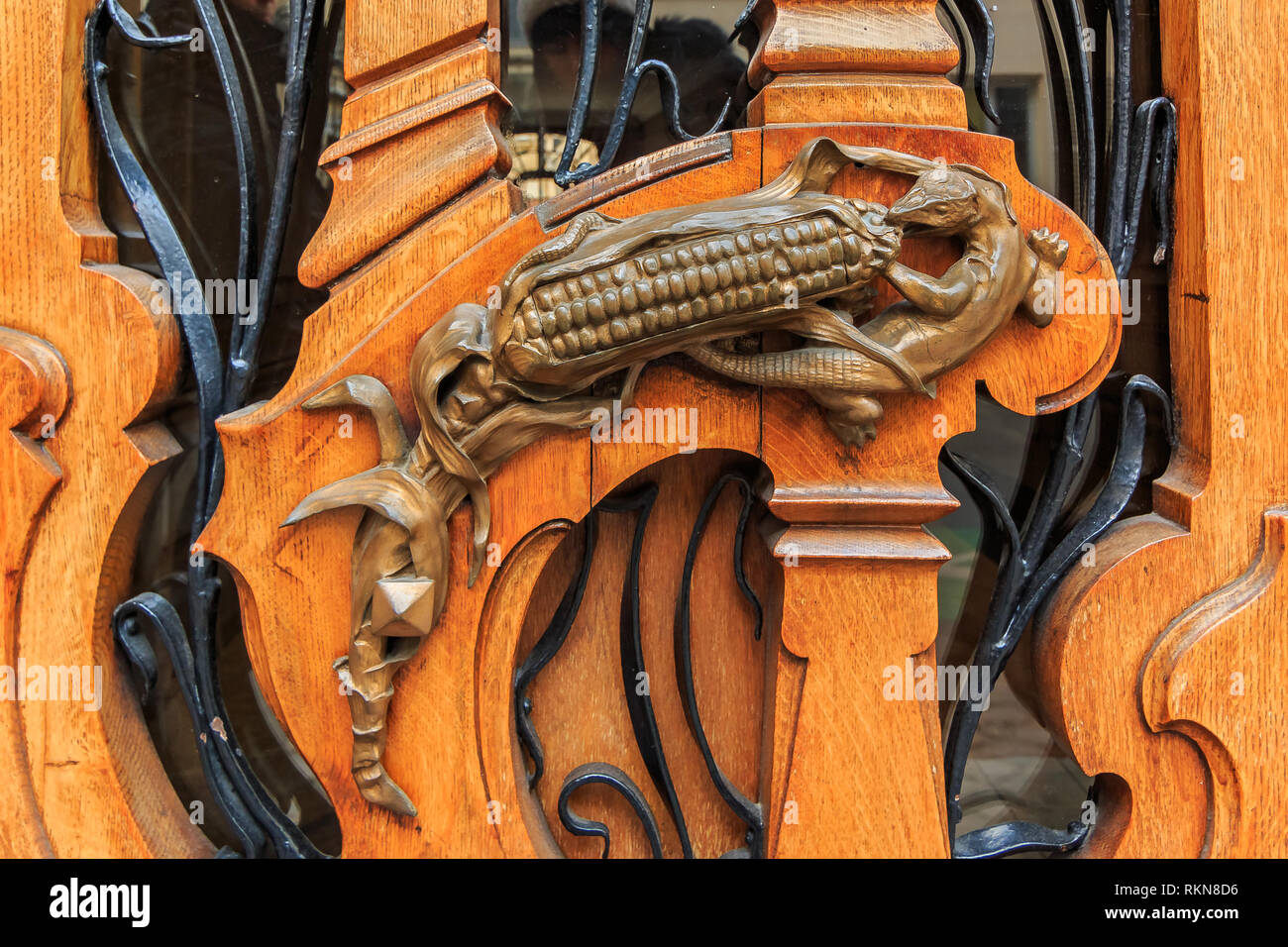 Art nouveau ouvragée porte de bois détail avec motif organique et une figurine en bronze d'un lézard de manger un épi de maïs pour une poignée de porte à Paris, France Banque D'Images