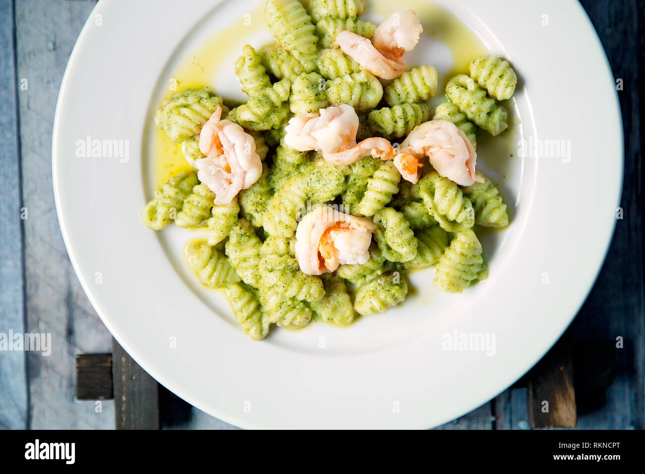 Gnocchi fait maison avec crevettes et sauce pesto servi sur un plaque blanche Banque D'Images
