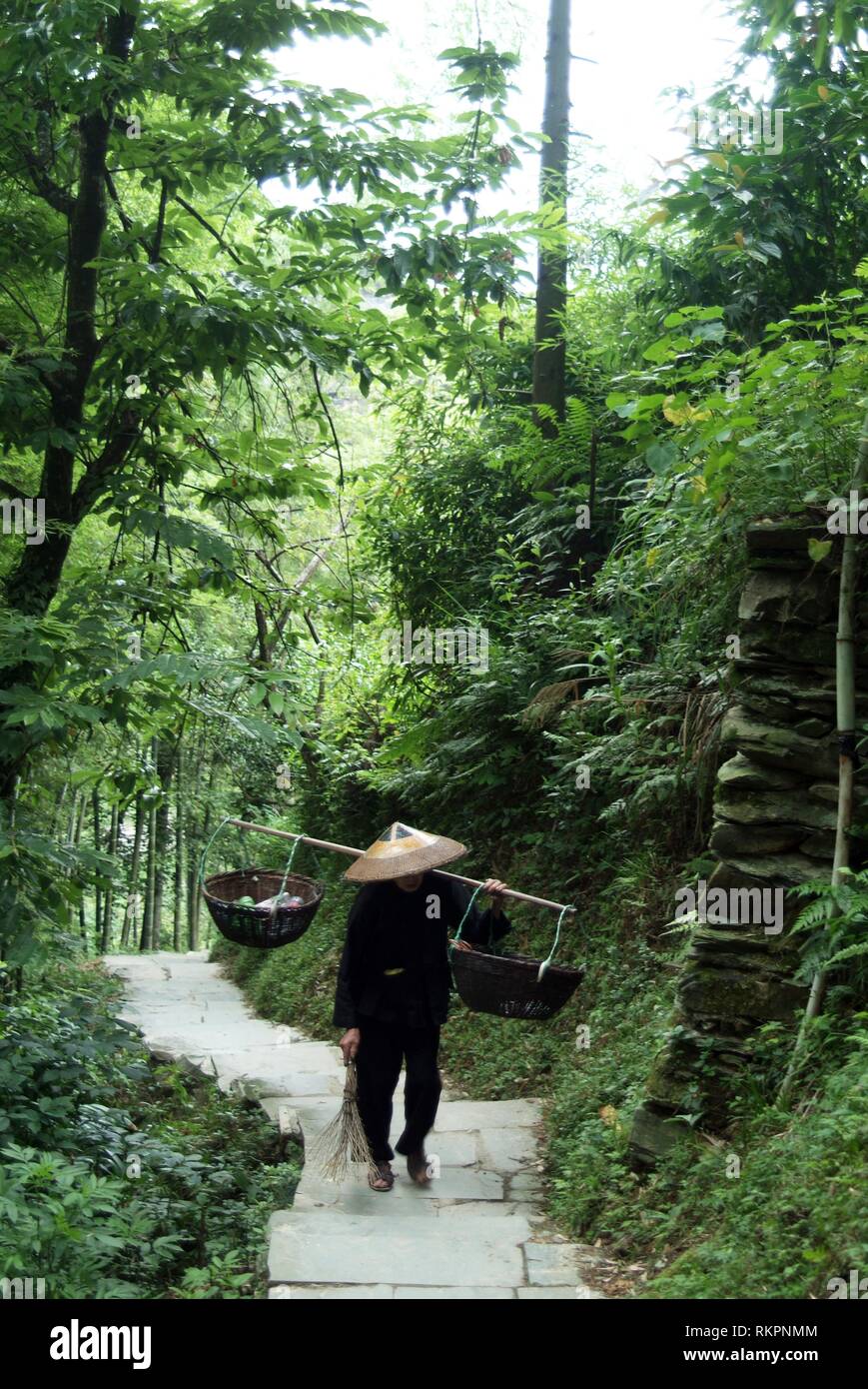 Un homme marche Zhuang le long d'un chemin de montagne dans la région de Ping'An, un petit hameau dans l'épine dorsale du Dragon- Longji terrasses de riz, Longshen Comté. Couper dans le c Banque D'Images