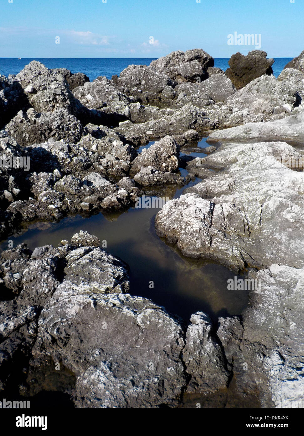 Rock noir volcanique typique de la côte de maratea avec des piscines de stagnation de l'eau de mer a apporté par les tempêtes Basilicate Italie Banque D'Images