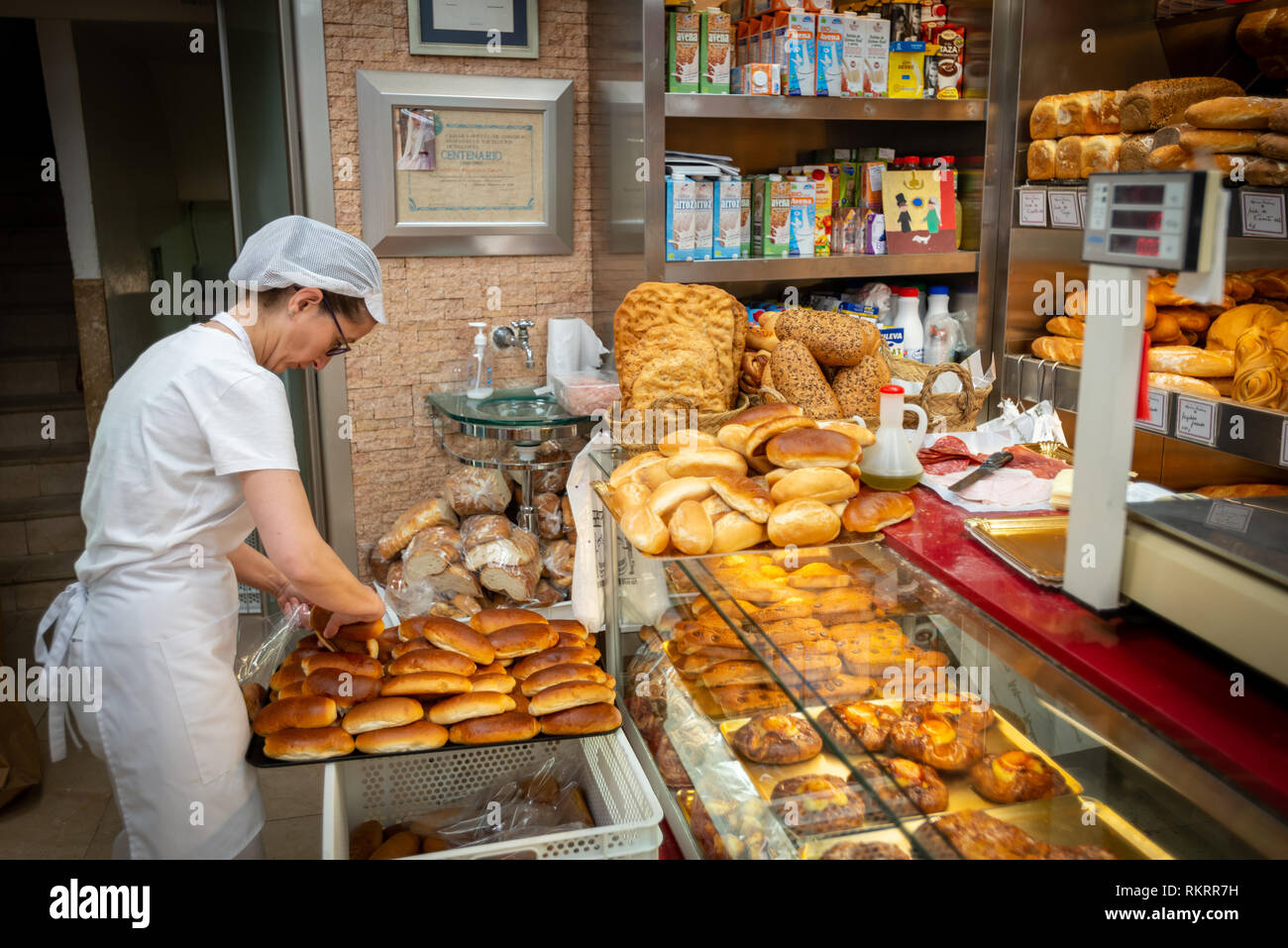 Un membre du personnel sortes de pain frais dans une pâtisserie, pâtisserie, dans la ville de Valence, Espagne. Banque D'Images