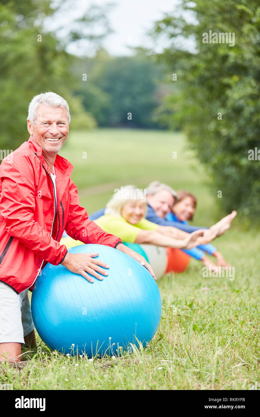 Senior Vital avec ballon de gymnastique et son groupe de réadaptation de sport dans le parc Banque D'Images