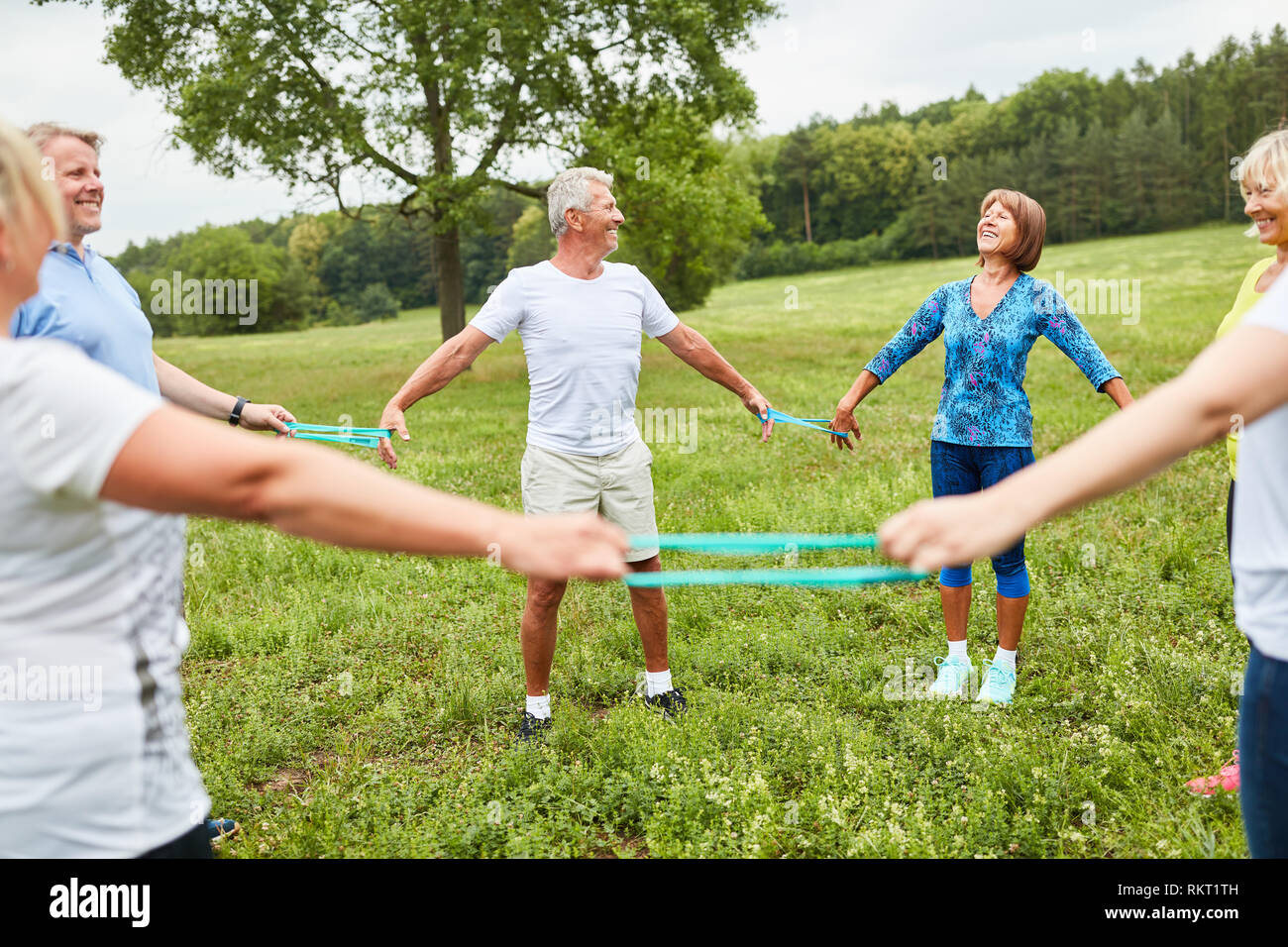 Un exercice d'aînés avec la bande élastique dans un cours de réhabilitation dans le parc Banque D'Images