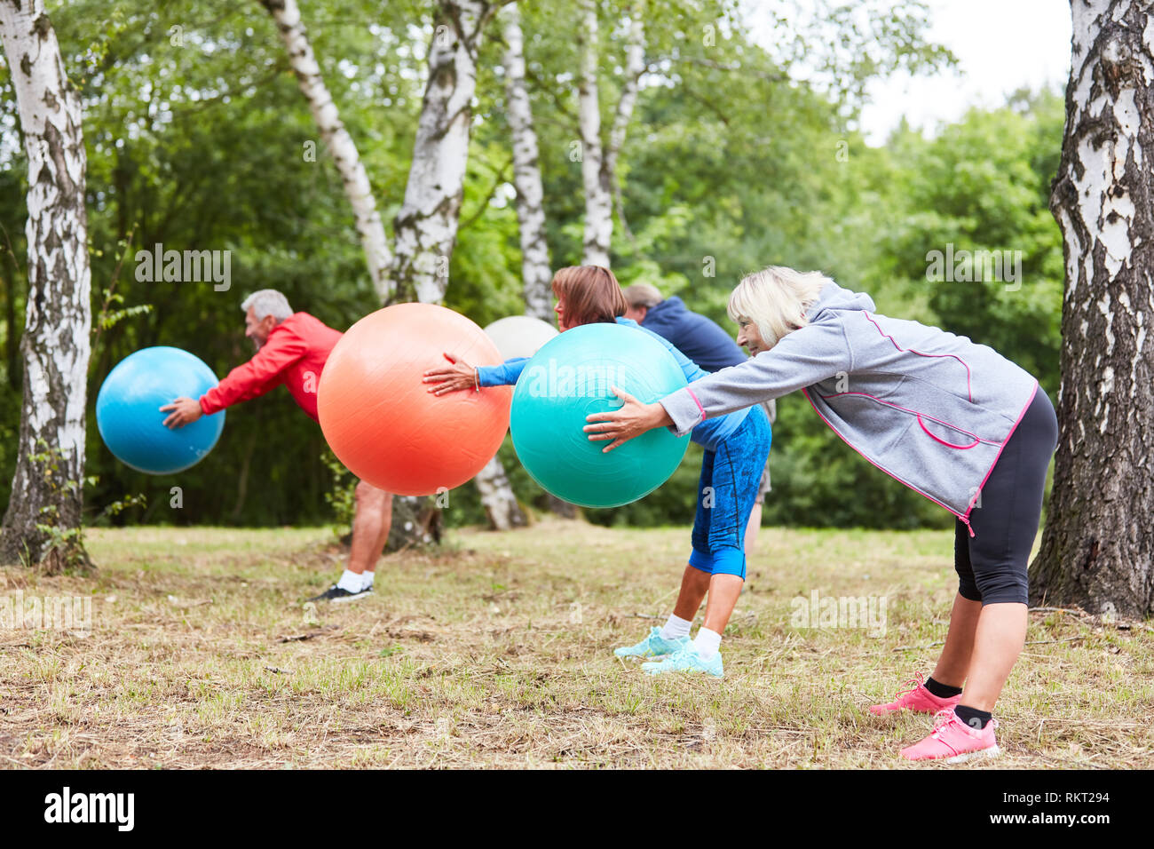 Les personnes âgées à faire des retour formation avec ballon de gymnastique en cours de réadaptation Banque D'Images
