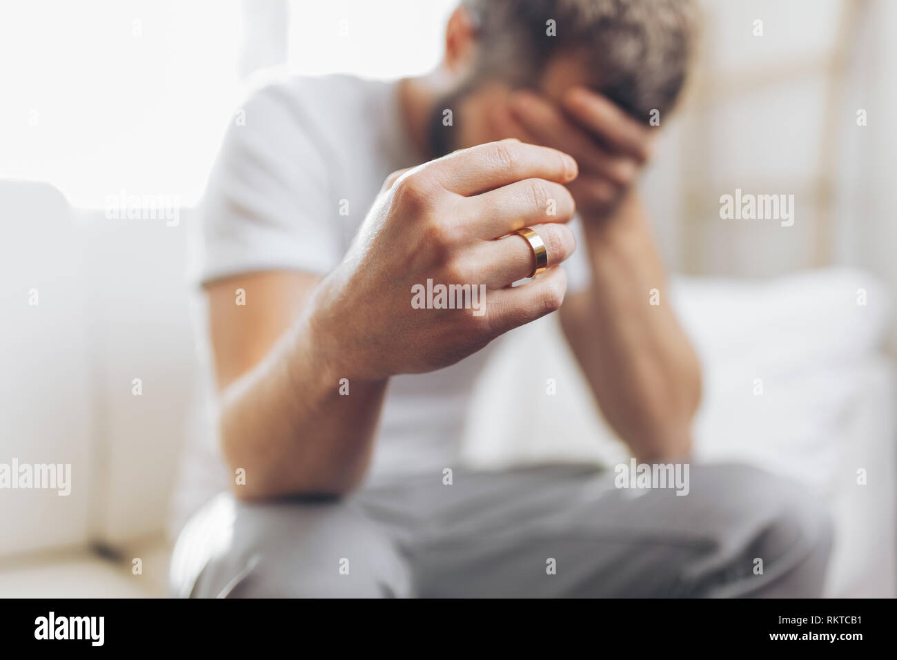 Le cœur brisé à la maison de l'homme tenant un anneau de mariage Banque D'Images