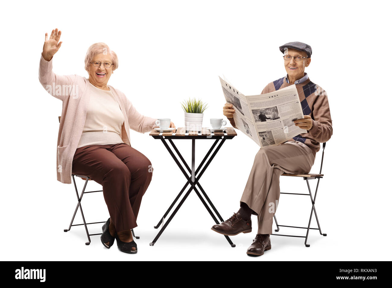 Portrait d'une femme âgée assise à une table avec une tasse de café et un homme âgé et lire un journal isolé sur blanc b Banque D'Images
