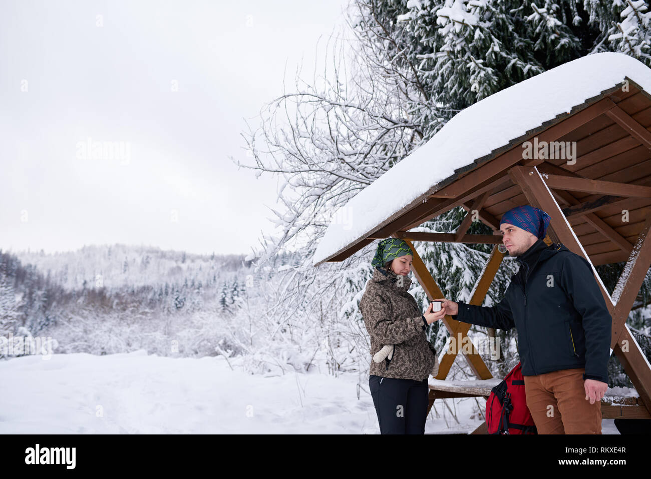 Smiling couple en matériel de randonnée dans un refuge permanent café partage tout en faisant une pause à partir d'une randonnée dans l'hiver Banque D'Images