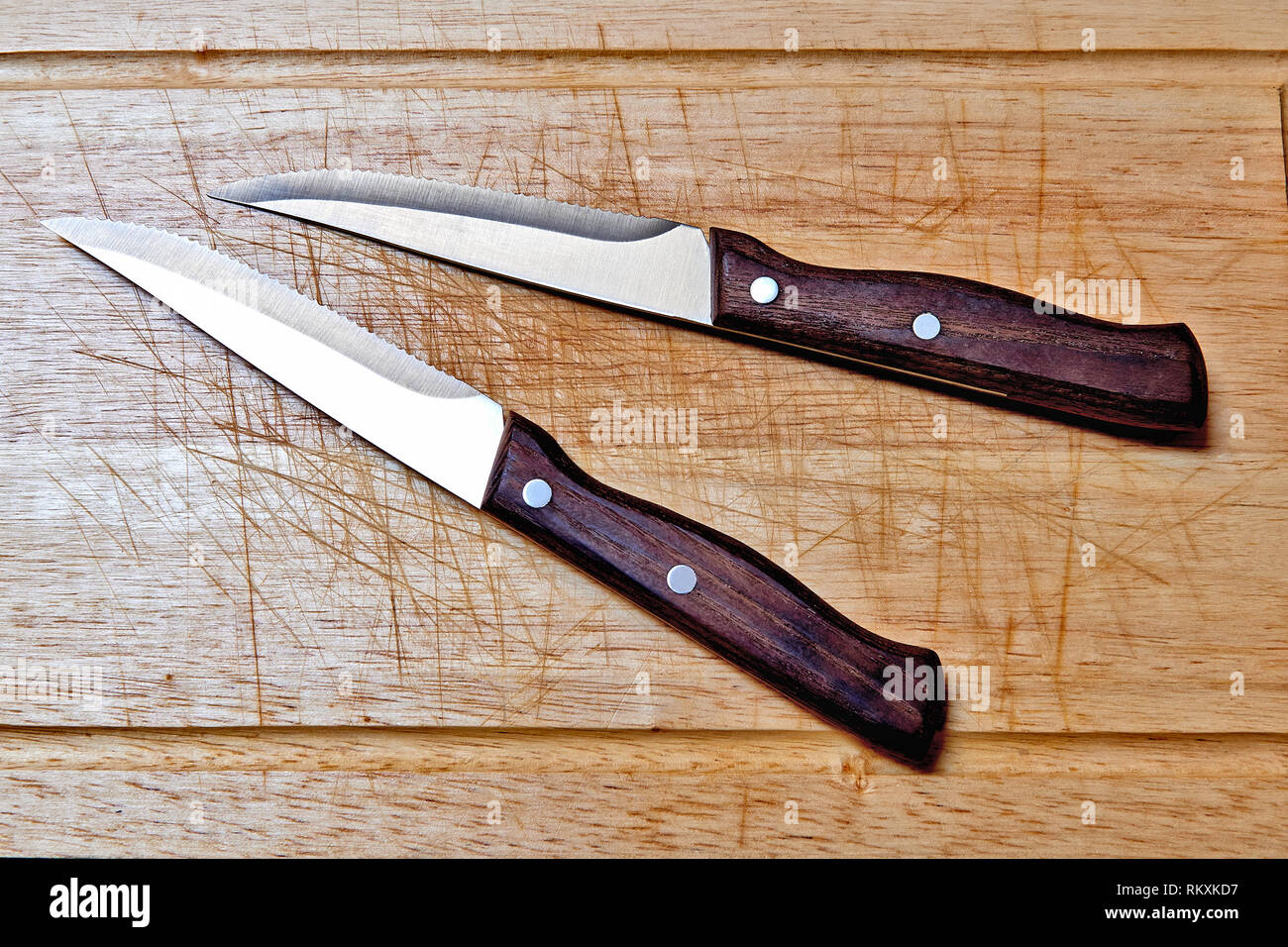 Deux couteaux steack sur planche en bois rayé et texturée, vue du dessus avec lumière naturelle Banque D'Images