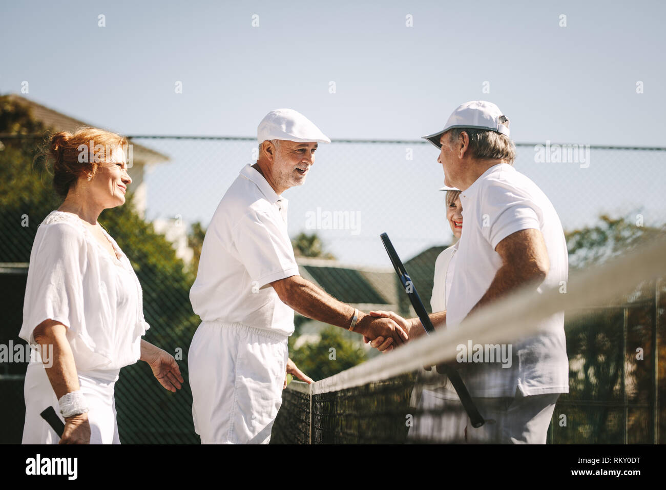 Senior men shaking hands standing on tennis après le match. Chaque message d'aînés d'autres après une partie de tennis en double mixte, debout près de la n Banque D'Images