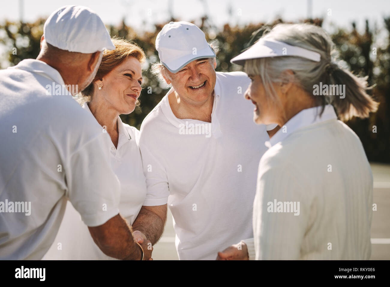 Smiling couples échanger des salutations après une partie de tennis. Chaque message d'autres cadres supérieurs après un match de tennis en double mixte. Banque D'Images
