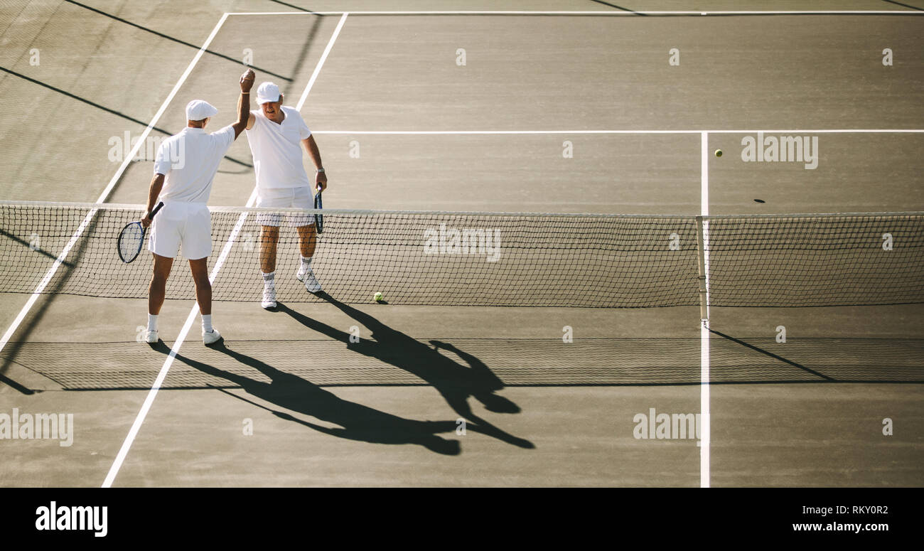 Les hommes jouent au tennis sur une journée ensoleillée. Les joueurs de tennis chaque message d'autres après une partie de tennis. Banque D'Images