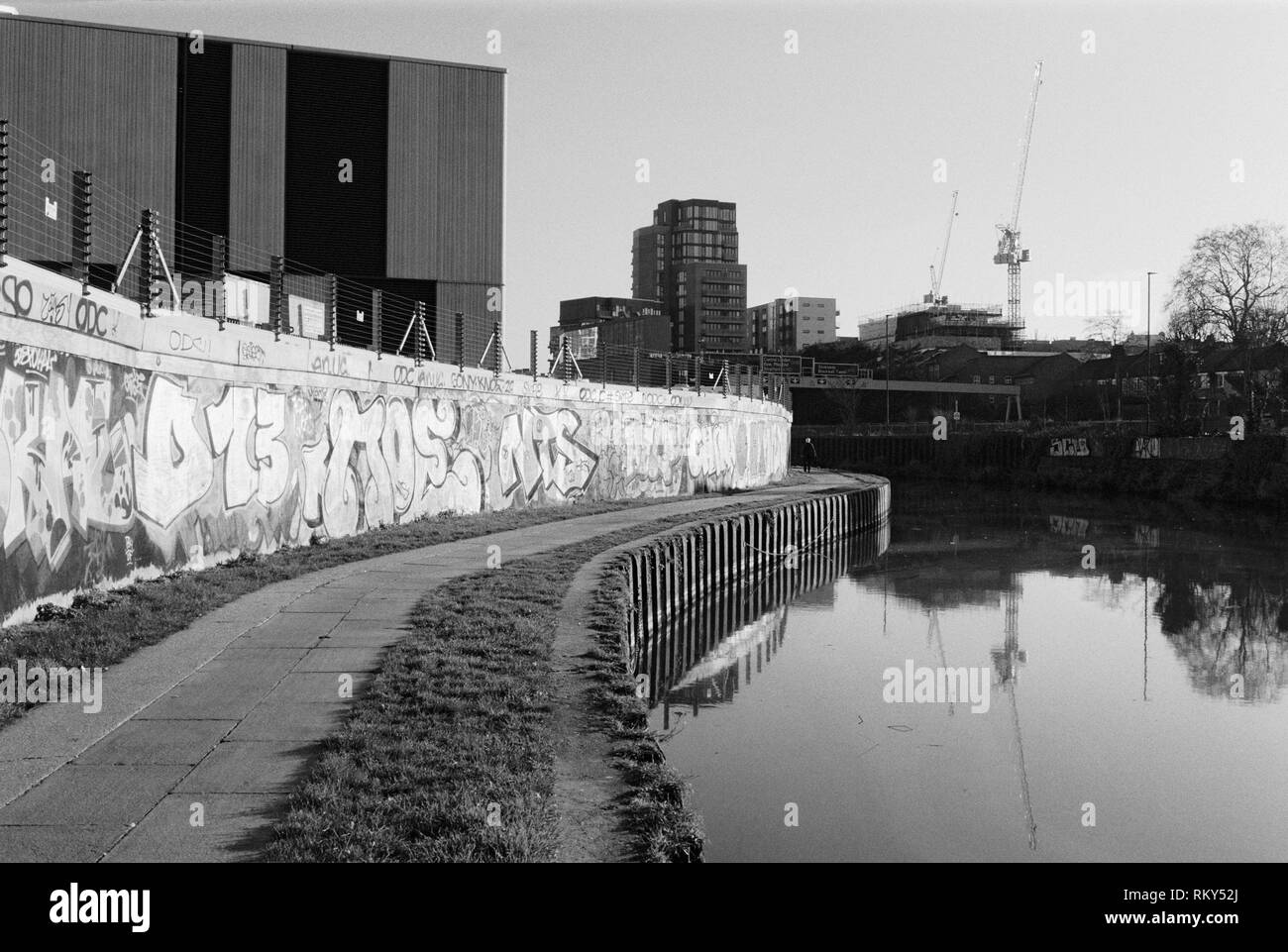 Mur de graffiti et sentier pédestre le long de la rivière Lea près de Bromley-By-Bow, East London, UK, avec des bâtiments en arrière-plan Banque D'Images