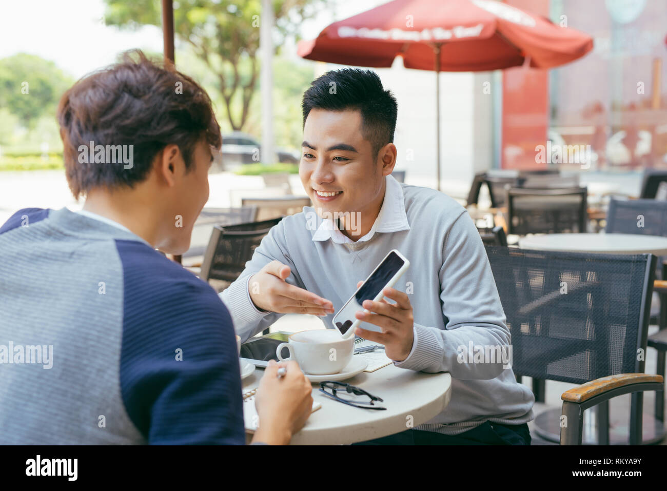 Contrôler les stocks. Deux partenaires travaillant sur l'ordinateur portable en souriant gaiement sur une réunion au café local - Image Banque D'Images