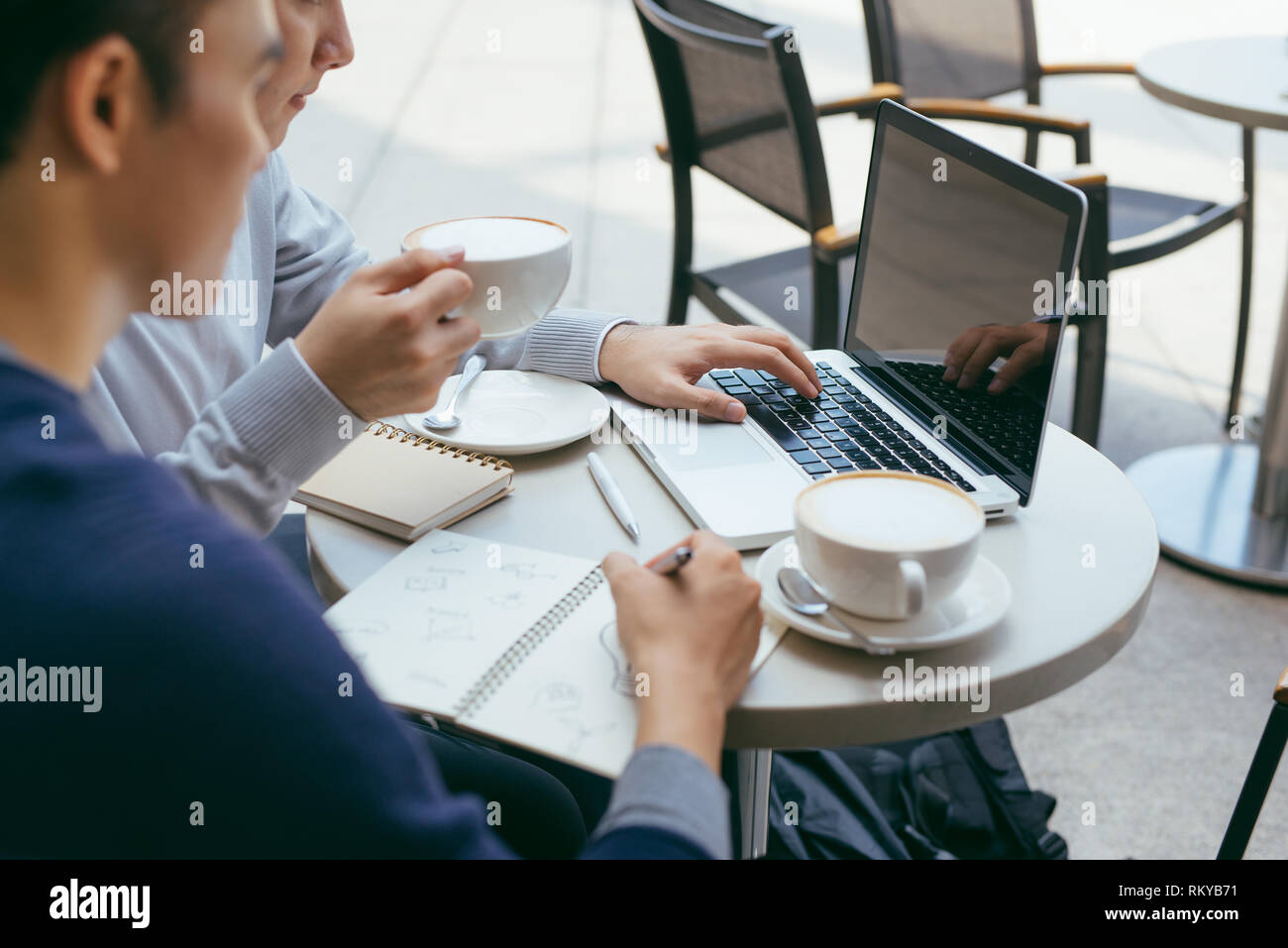 Deux jeunes hommes sont en pleine discussion dans un café. - Image Banque D'Images
