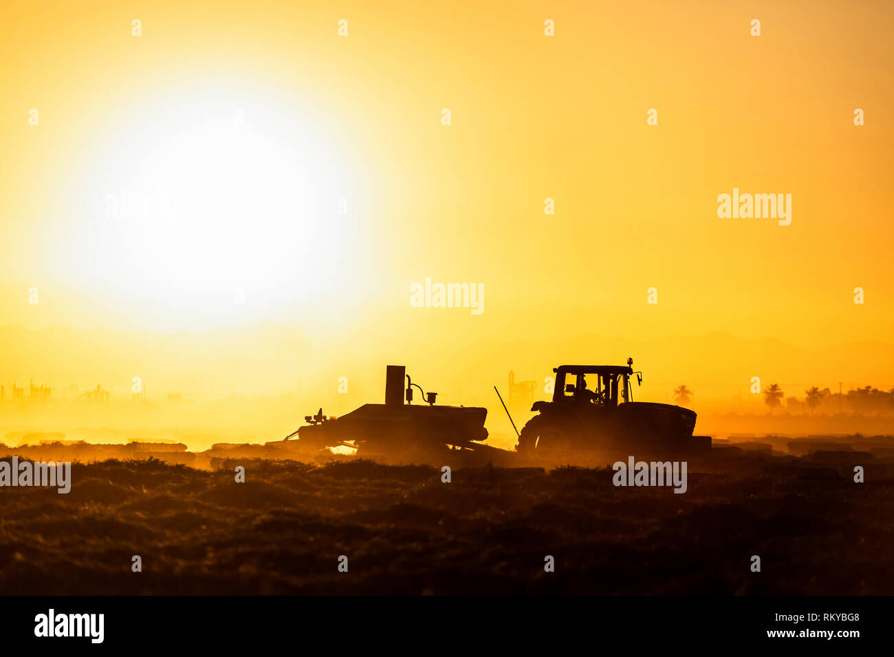 Plan large de l'agriculture d'une silhouette de tracteur au lever du soleil. Banque D'Images