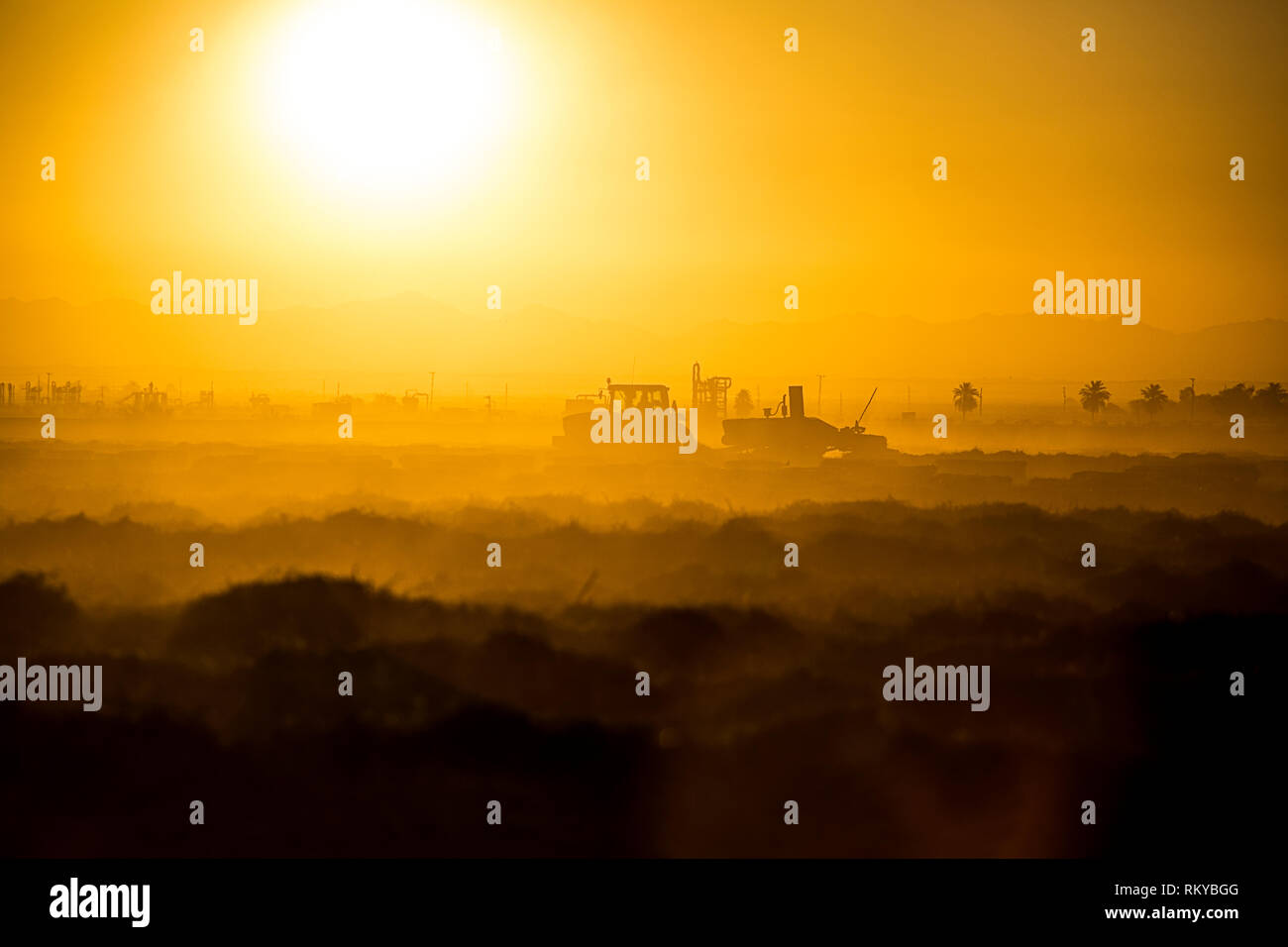 Plan large de l'agriculture d'une silhouette de tracteur au lever du soleil. Banque D'Images
