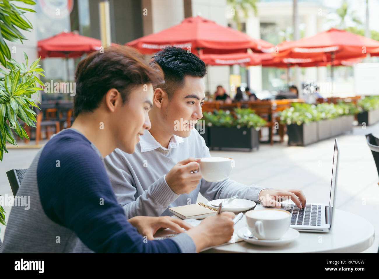 Deux jeunes hommes sont en pleine discussion dans un café. - Image Banque D'Images