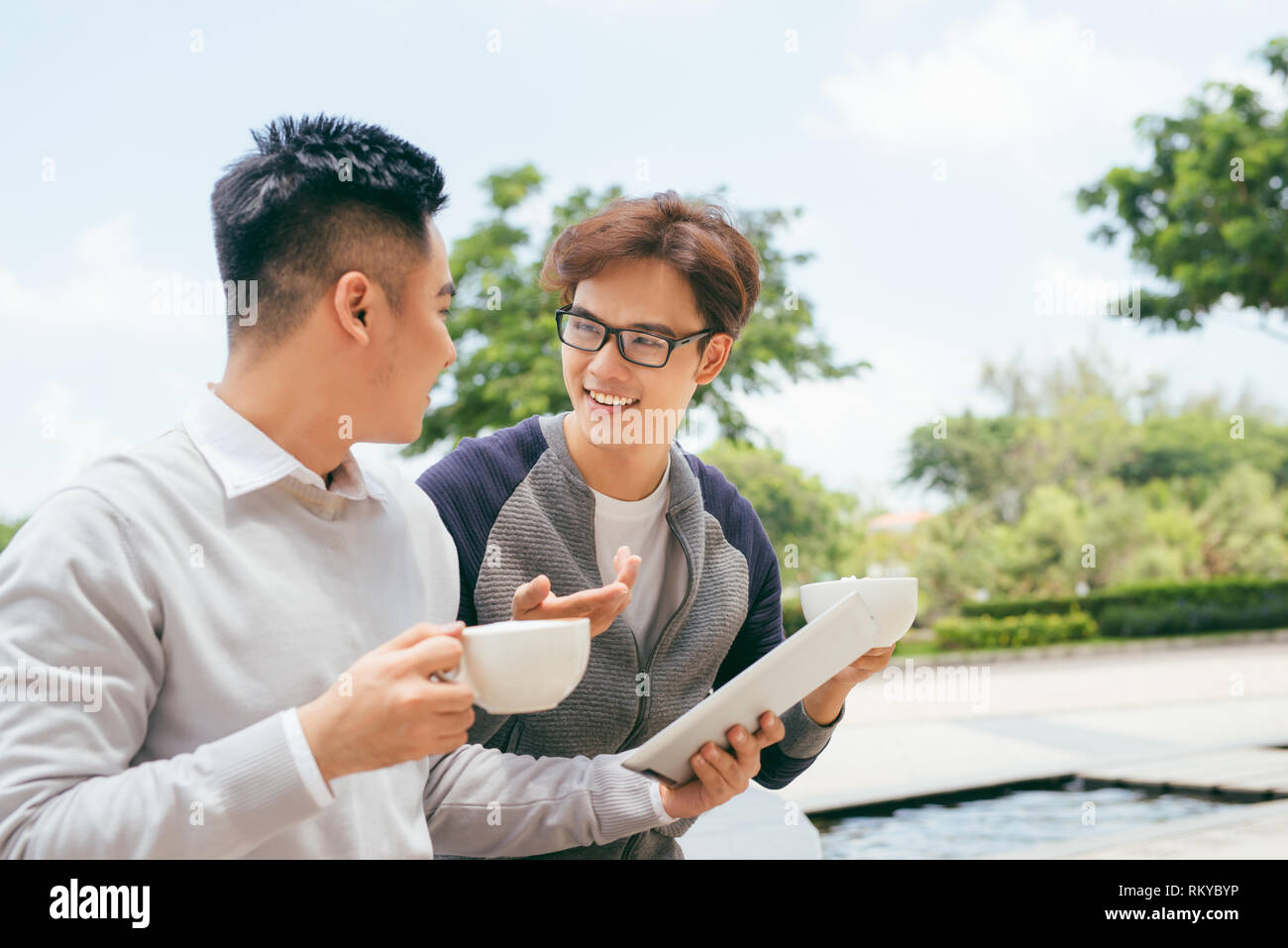 Deux hommes à l'aide de l'ordinateur tablette Internet, amis asiatiques gars assis au Café Lumière Naturelle Banque D'Images