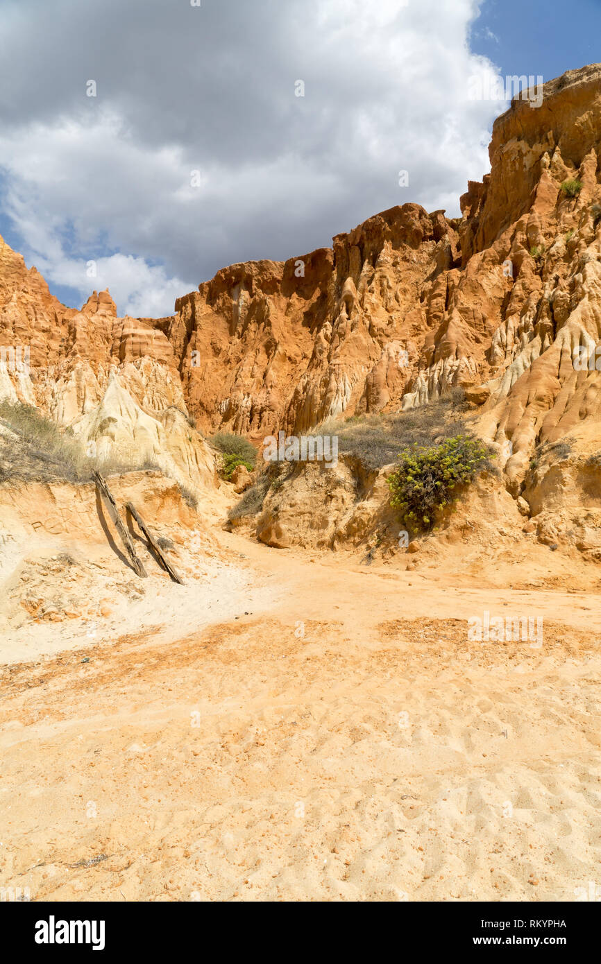 Hautes falaises le long de la plage de Falesia et l'océan Atlantique à Albufeira, Algarve, Portugal. Journée ensoleillée, ciel bleu avec des nuages orageux. Banque D'Images