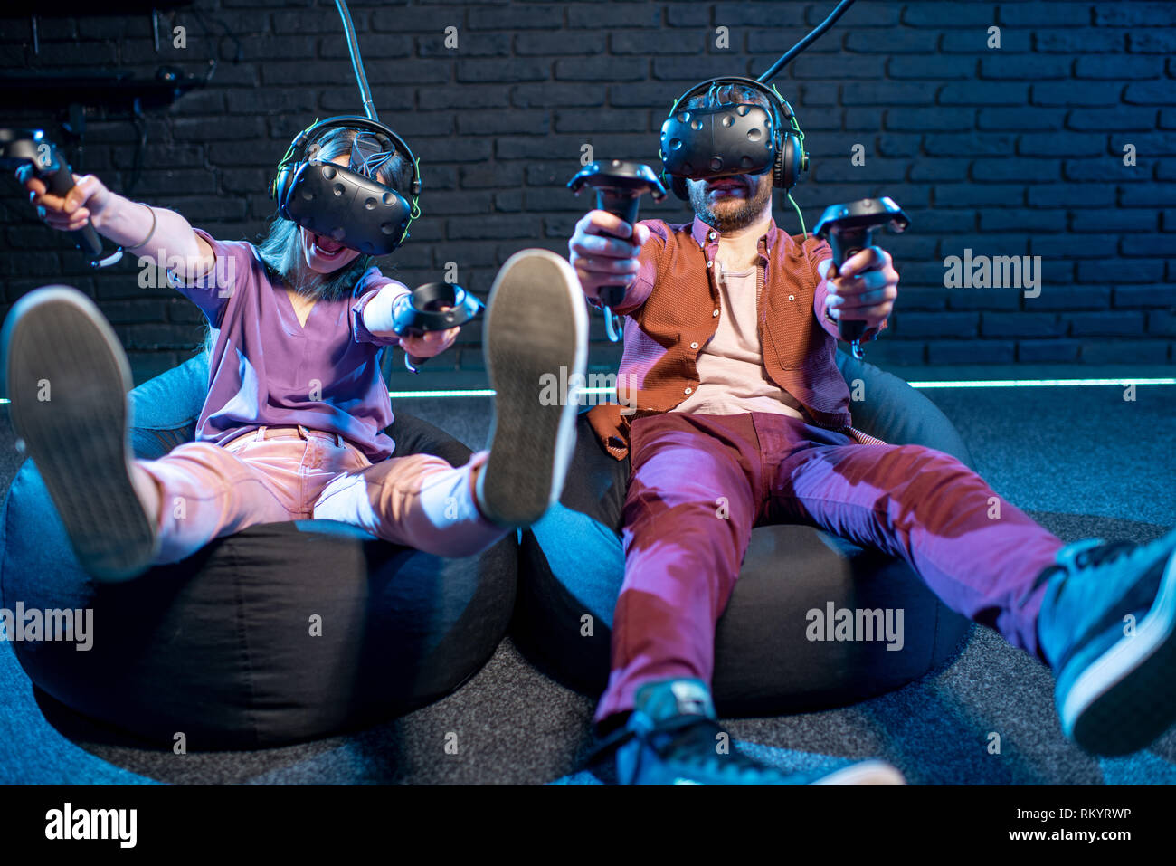 L'homme et de la femme de tir avec les manettes de jeu tout en jouant en réalité virtuelle à l'aide de casques VR dans la salle de jeu Banque D'Images