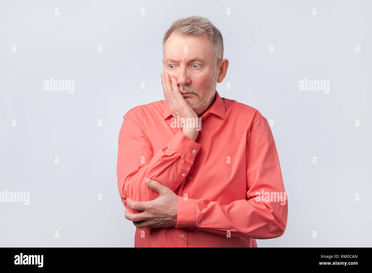 Senior man in red shirt à penser à sa vie. Banque D'Images
