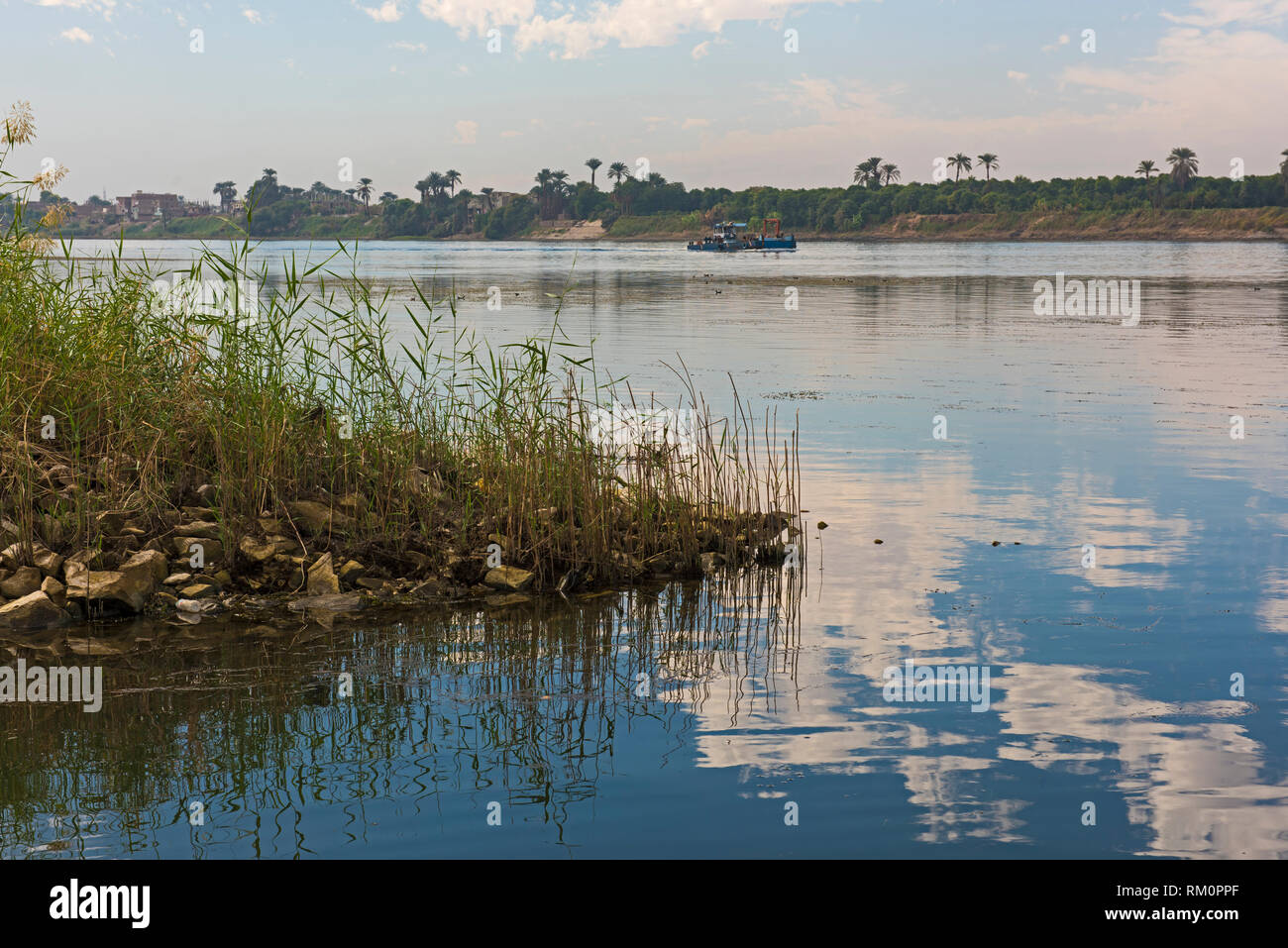 Paysage panoramique Vue sur campagne rurale de grand fleuve du Nil avec l'herbe roseaux en premier plan et la réflexion dans l'eau. Banque D'Images