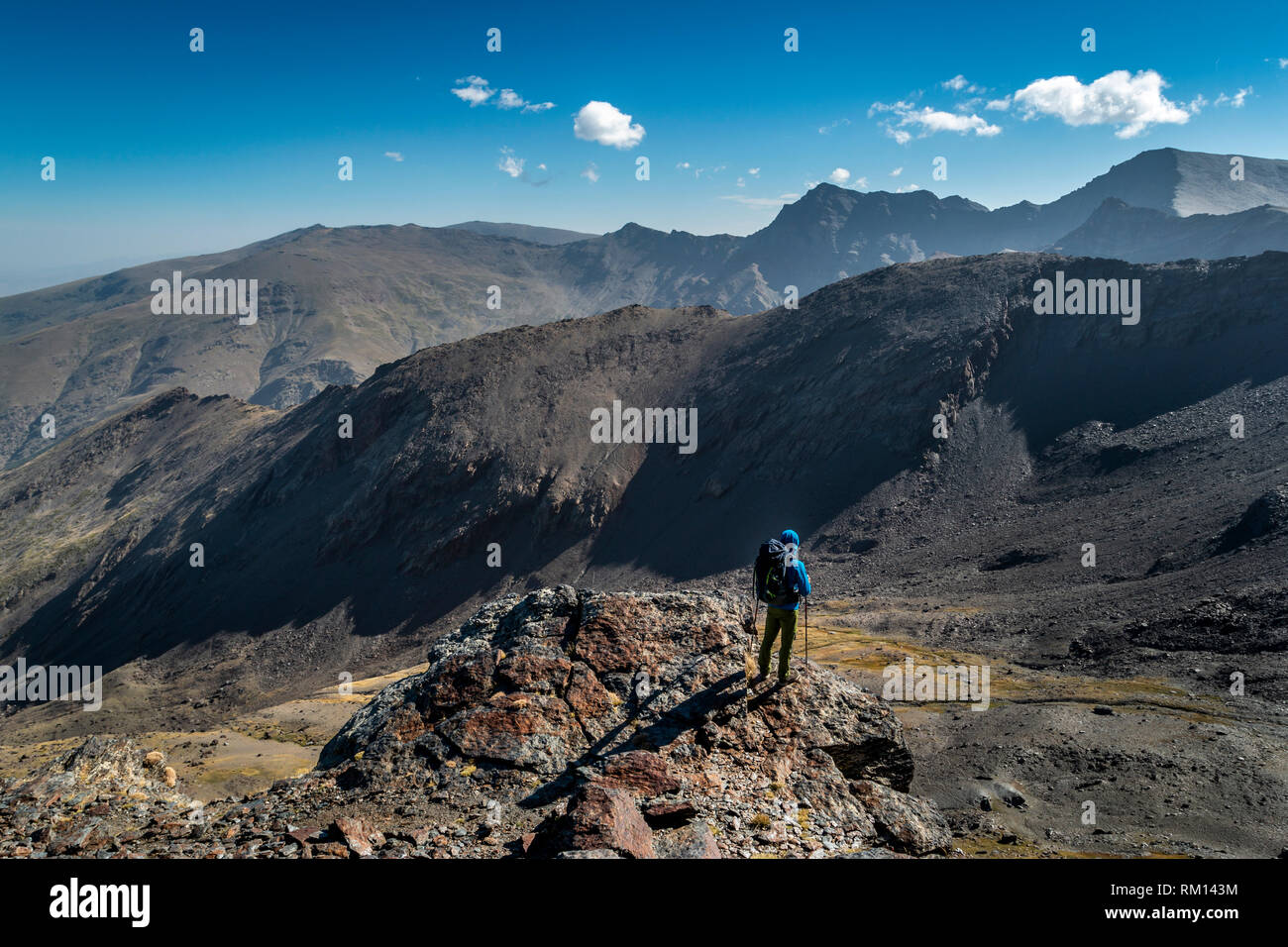 Vue latérale du méconnaissable d'alpiniste avec sac à dos, debout sur la falaise et regarder les montagnes magnifiques aux beaux jours Banque D'Images