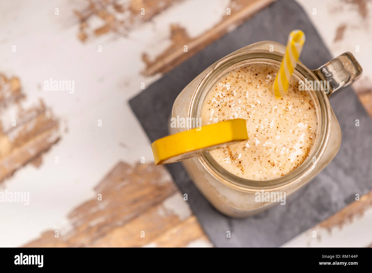 Au-dessus de la savoureuse boisson fraîche dans une tasse en verre avec le tube en plastique et de la coupe de fruits sur table en bois sur les montagnes russes Banque D'Images