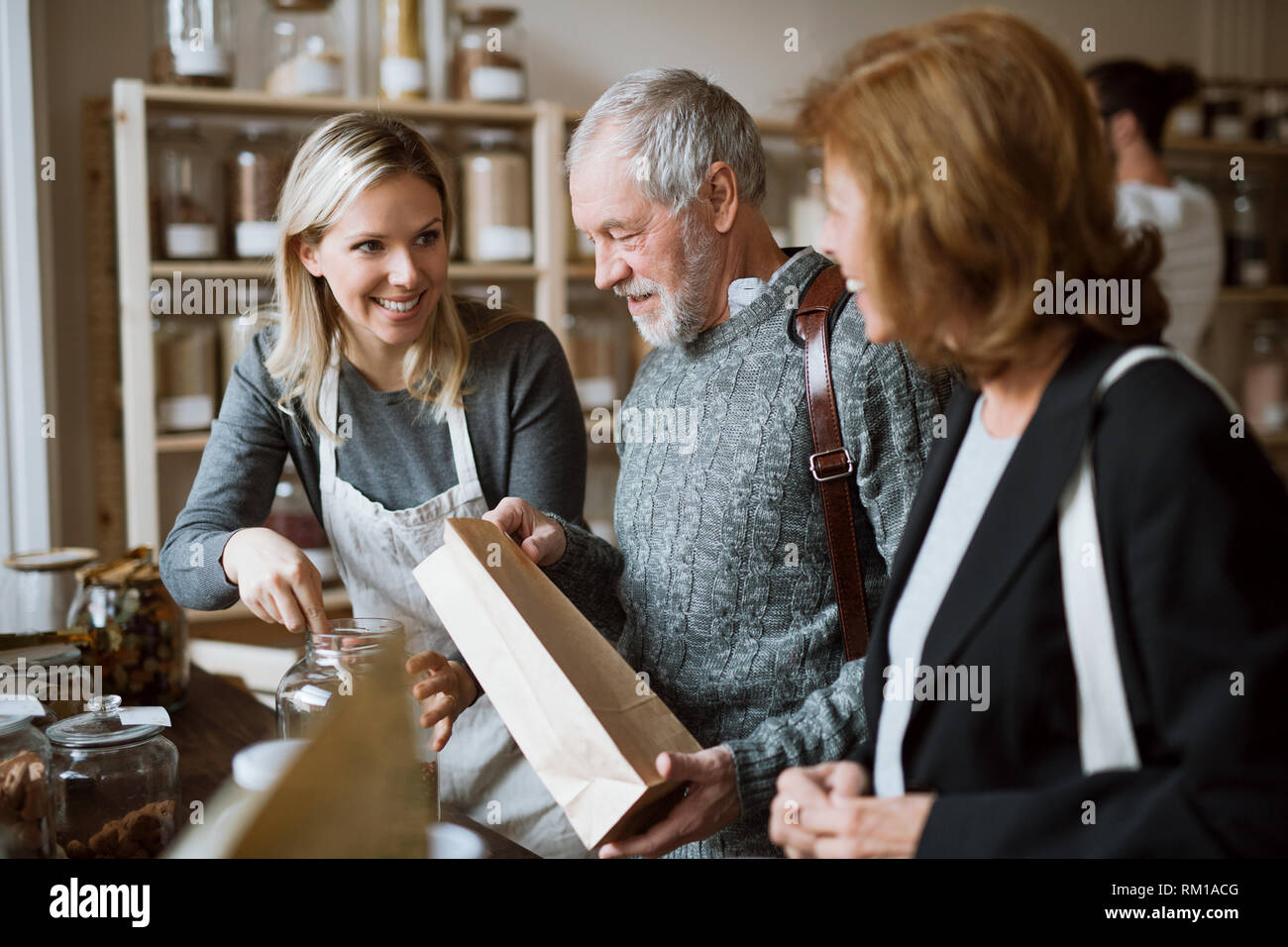 Une femme shop assistant servant un couple dans un magasin sans déchets. Banque D'Images