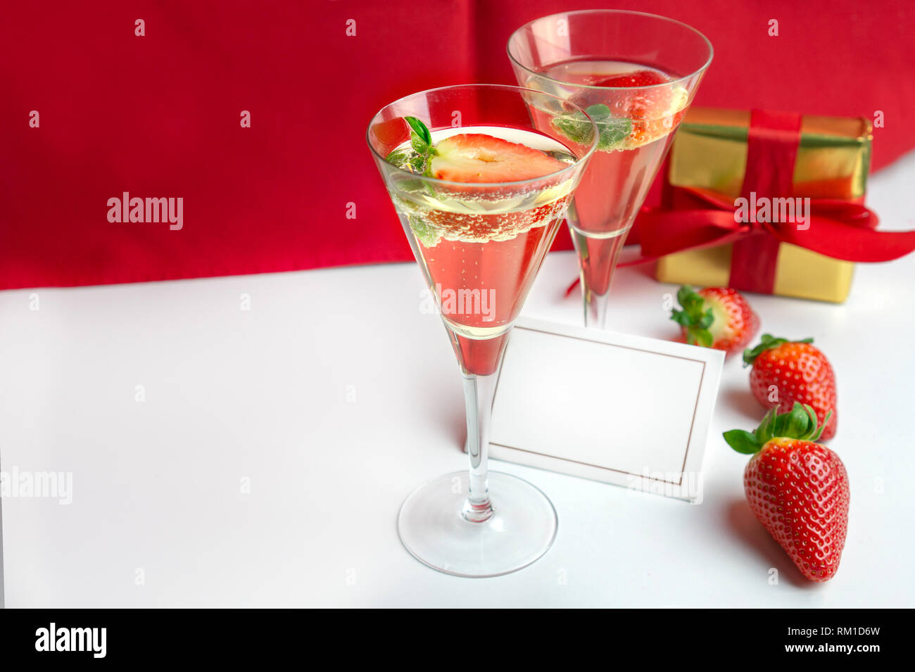 Deux verres de champagne avec des fraises et une carte vide entre eux avec un cadeau à l'arrière-plan . Concept de la Saint-Valentin Banque D'Images