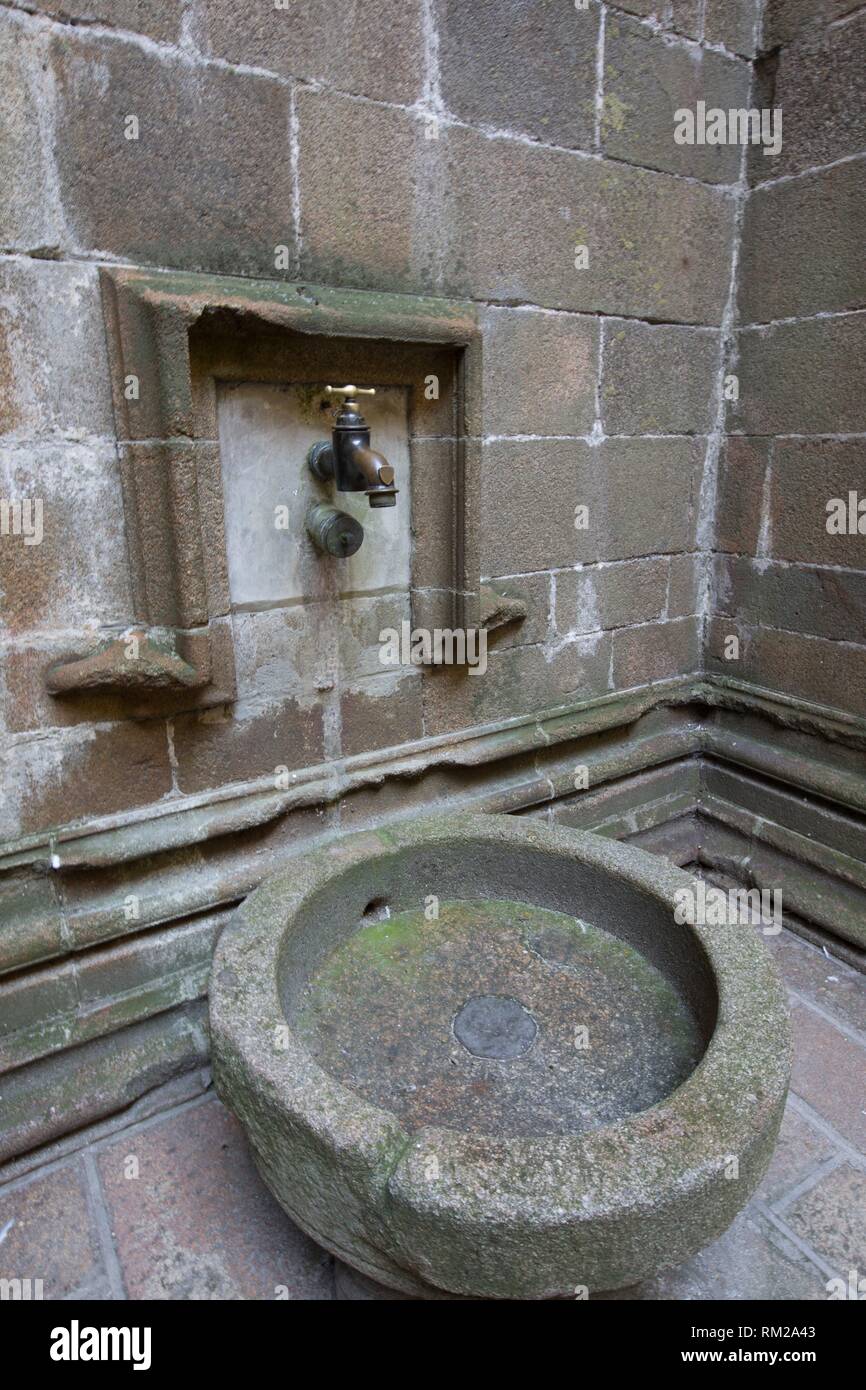Fontaine en pierre et de grandes robinet robinet laiton à l'intérieur du Mont Saint Michel. Normandie, France Banque D'Images